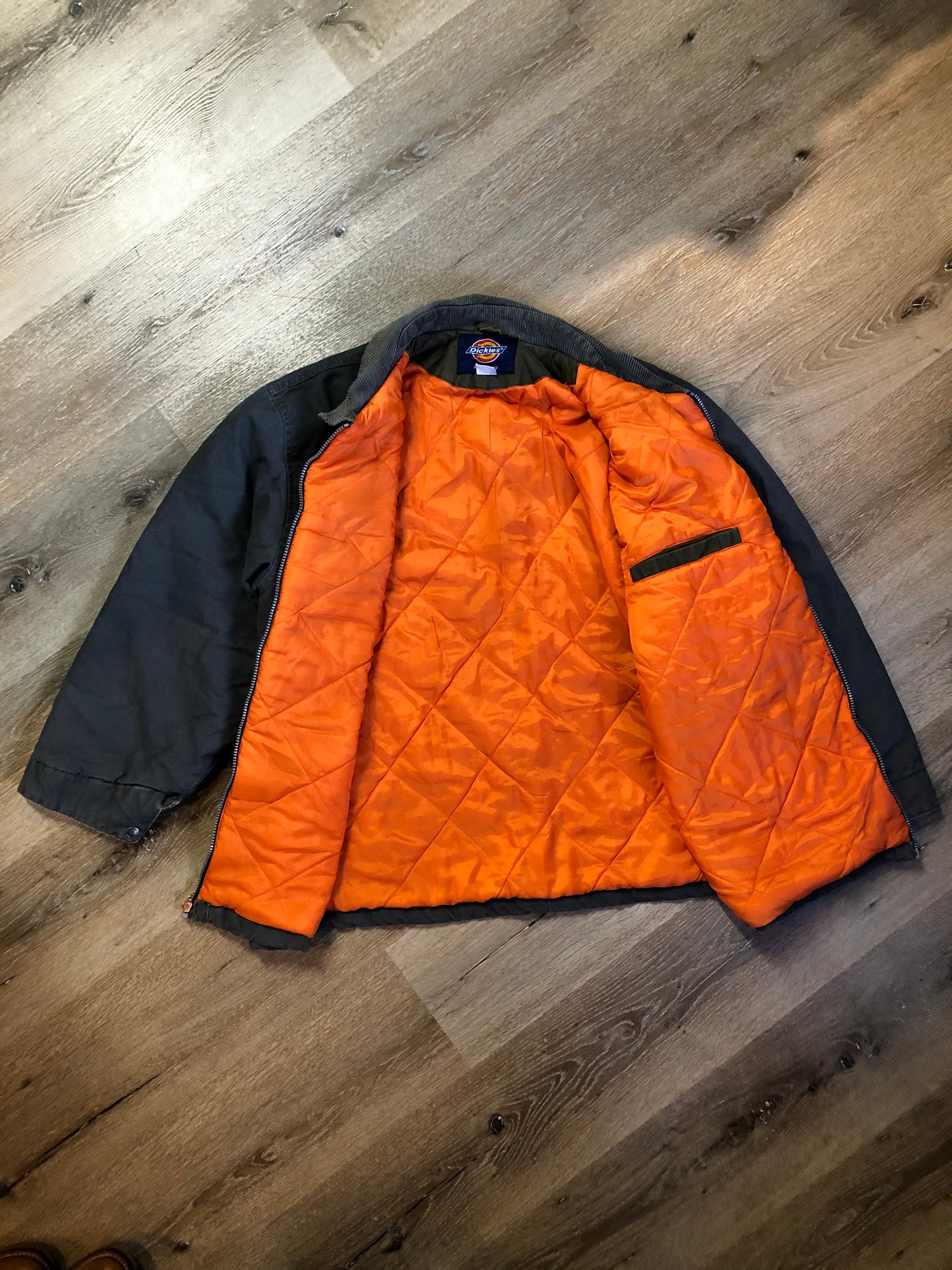 Kingspier Vintage - Dickie’s grey insulted chore jacket with grey corduroy collar, zipper closure, slash pockets, one zip pocket on the chest, one inside pocket and bright orange quilted lining. Size large.