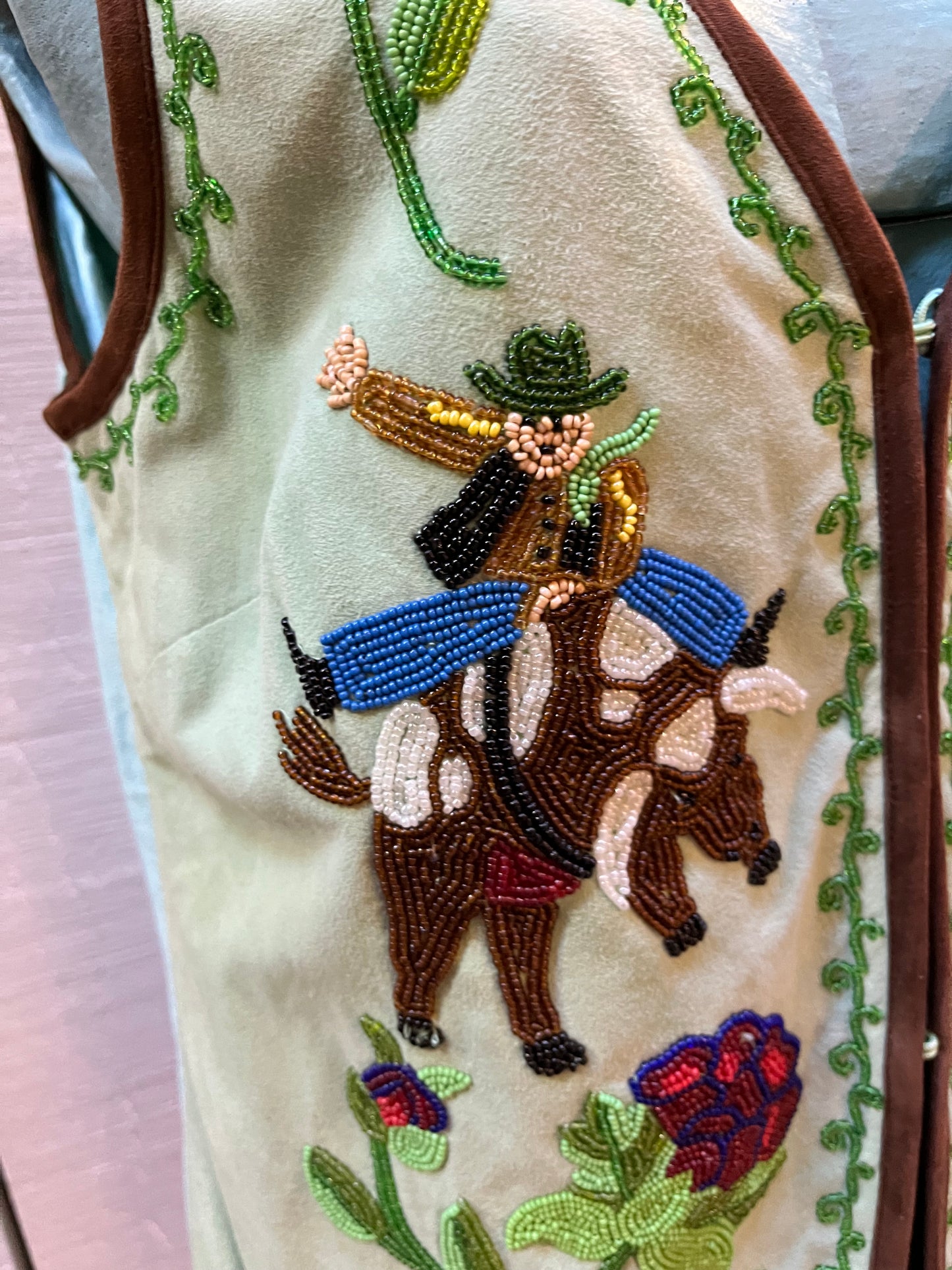 Double D Ranch light green goat suede vest with brown fringe detail, hook and eye closure, cotton/ linen back panel, satin lining and a western cowboy and desert rose design that is hand beaded.
Made in India
Size Medium