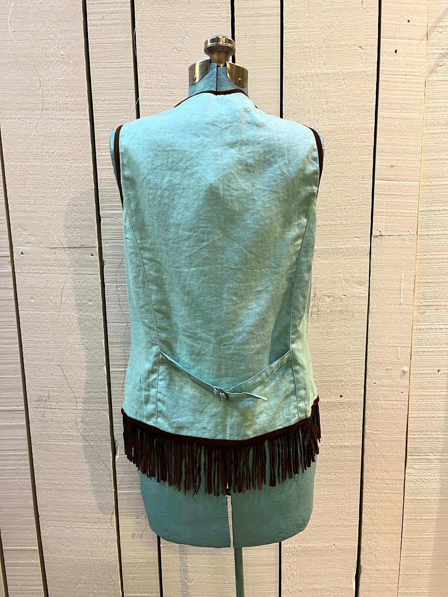 Double D Ranch light green goat suede vest with brown fringe detail, hook and eye closure, cotton/ linen back panel, satin lining and a western cowboy and desert rose design that is hand beaded.
Made in India
Size Medium