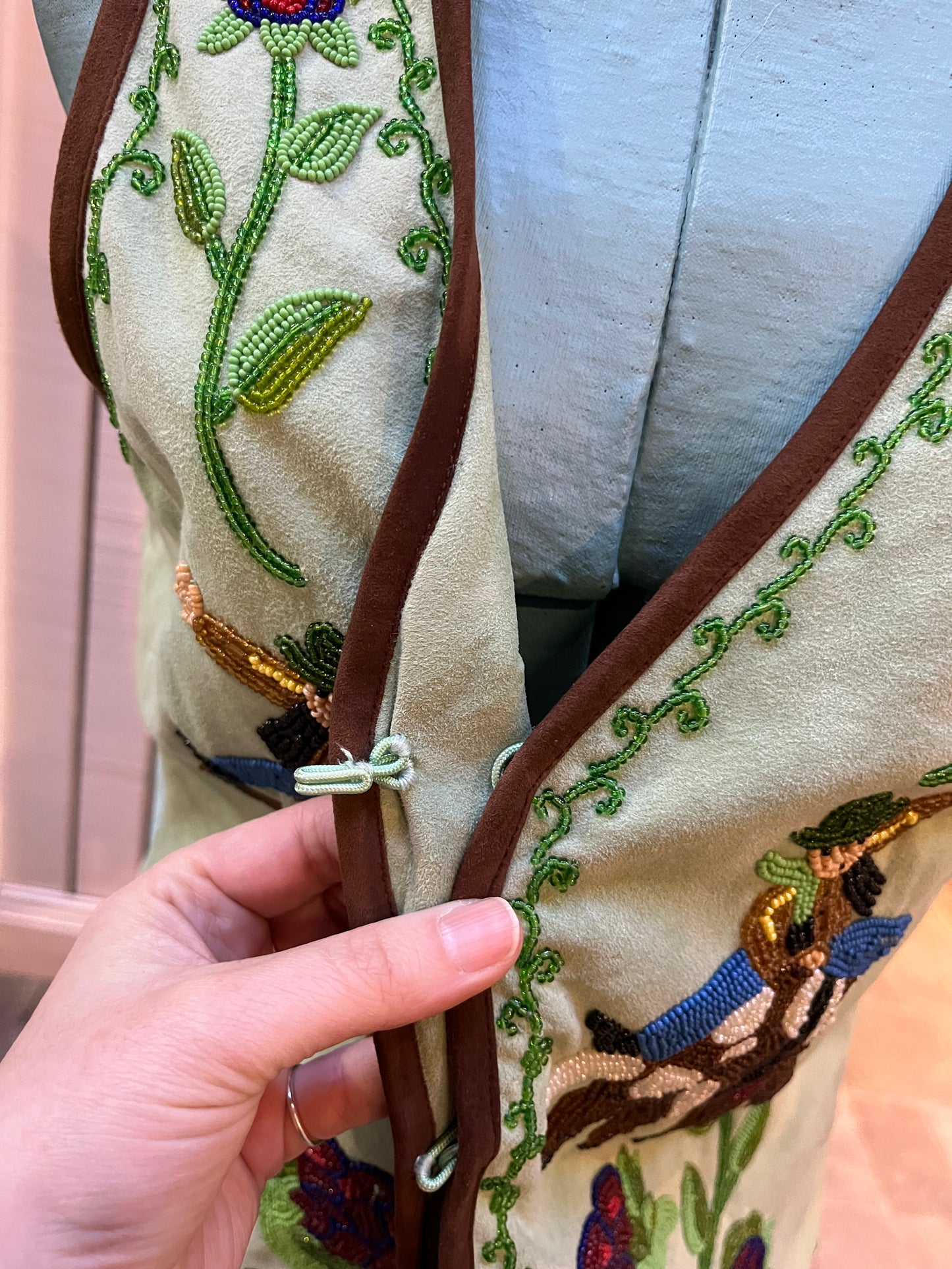 Double D Ranch light green goat suede vest with brown fringe detail, hook and eye closure, cotton/ linen back panel, satin lining and a western cowboy and desert rose design that is hand beaded.
Made in India
Size Medium