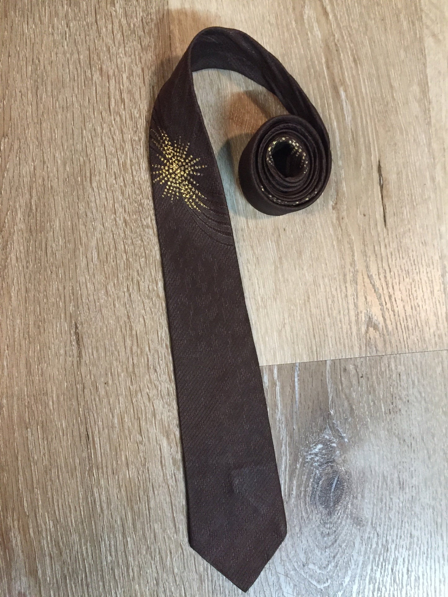 Kingspier Vintage - Frank Struser Original Necktie in brown with gold starburst design. Fibres unknown.
Length: 56.6” 
Width: 2.5” 
This tie is in excellent condition.