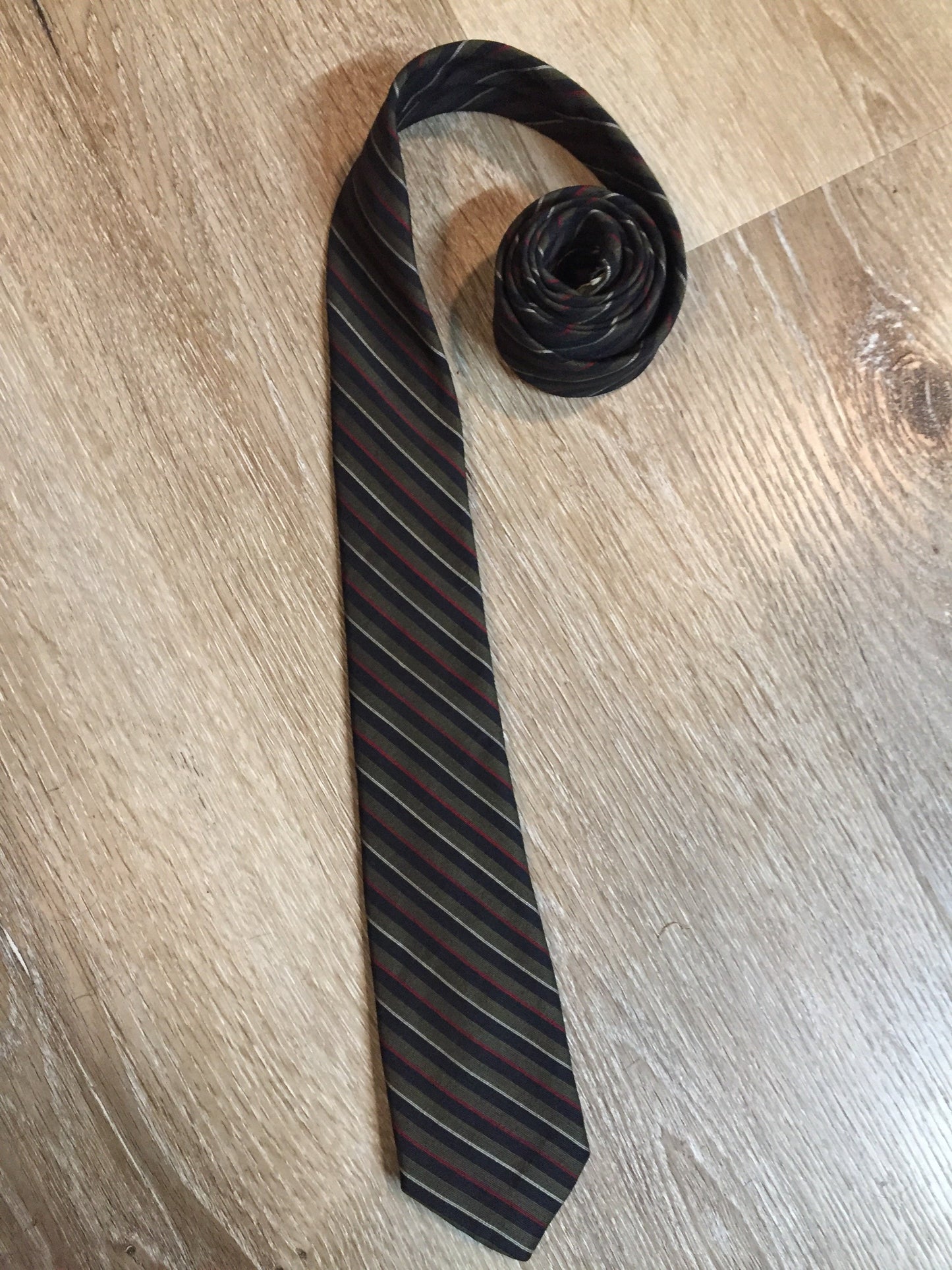 Kingspier Vintage - Tara Poplin by Park Lane of Canada Dacron and wool blend wash n’ wear tie with green, black, red and white stripes.
Length: 56”
Width: 2.5”
This tie is in excellent condition.