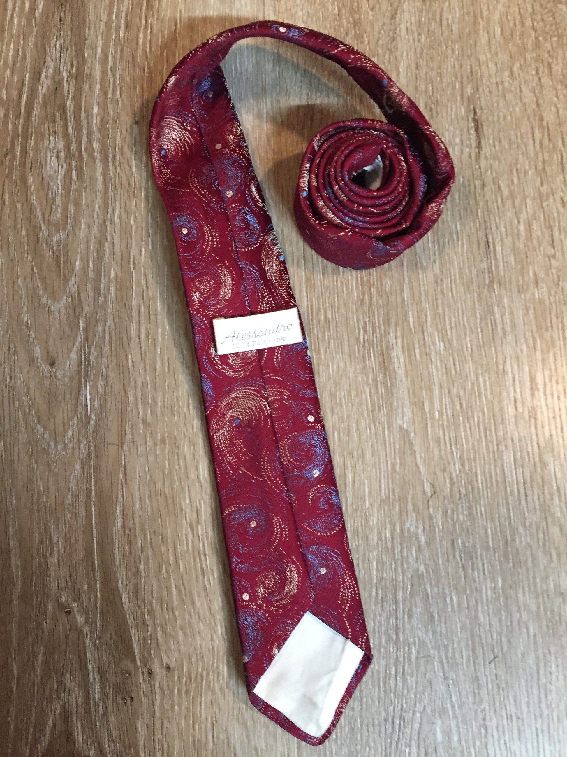 Kingspier Vintage - Alessandro 100% polyester tie with red, blue and cream subtle swirl design.
Length: 56.6”
Width: 2.5” 
This tie is in excellent condition.