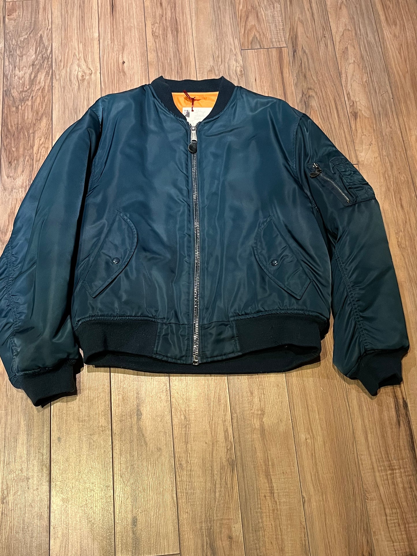 Vintage USAF Cobles Clothing Division Blue Flyer’s Man Intermediate MA. 1 Jacket. Based on original MIL-J-8279E.
100% nylon shell with polyester fill, blaze orange safety lining, zipper closure, two front slash pockets and a pocket on the left arm.
Size Medium