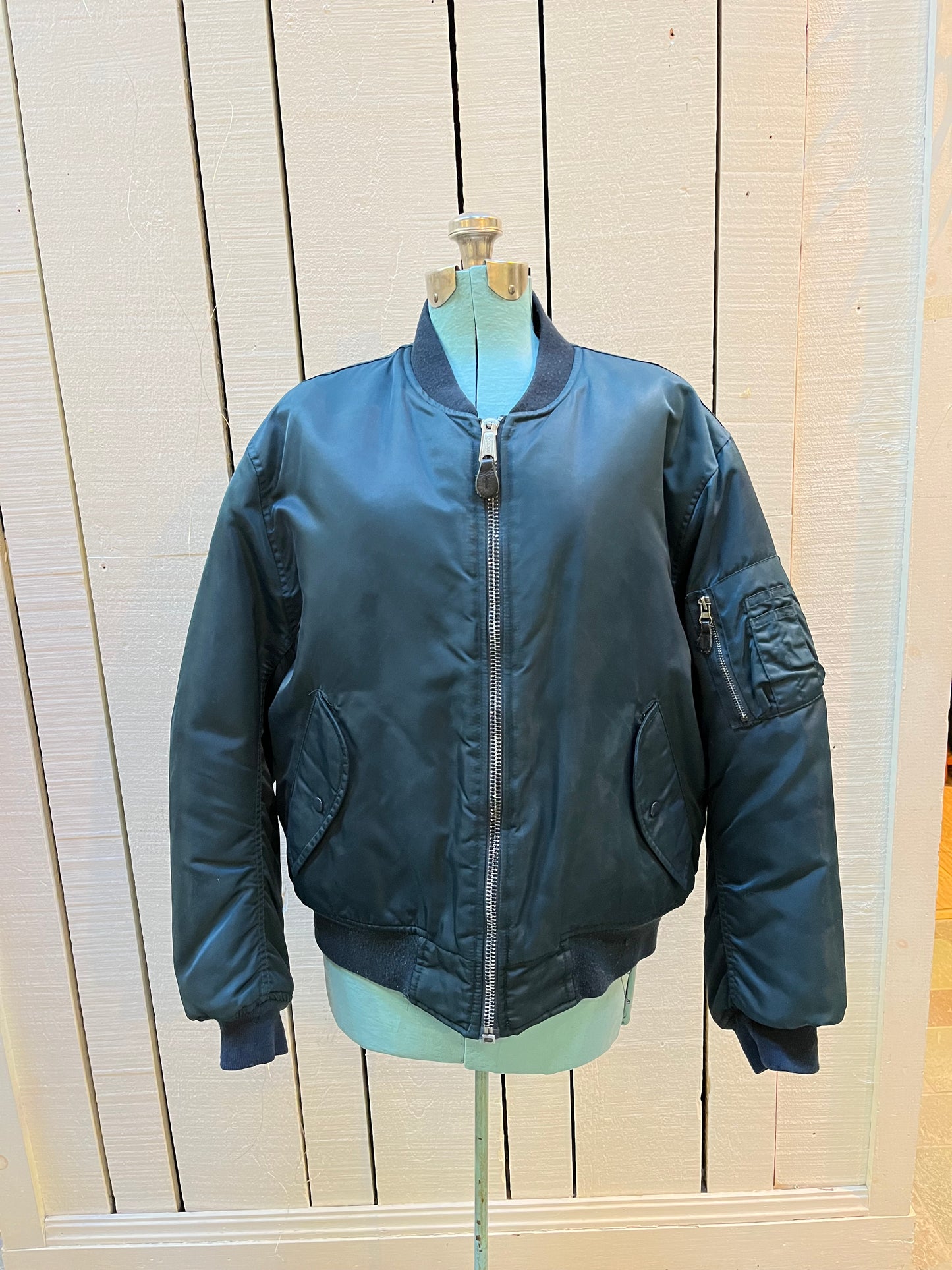 Vintage USAF Cobles Clothing Division Blue Flyer’s Man Intermediate MA. 1 Jacket. Based on original MIL-J-8279E.
100% nylon shell with polyester fill, blaze orange safety lining, zipper closure, two front slash pockets and a pocket on the left arm.
Size Medium