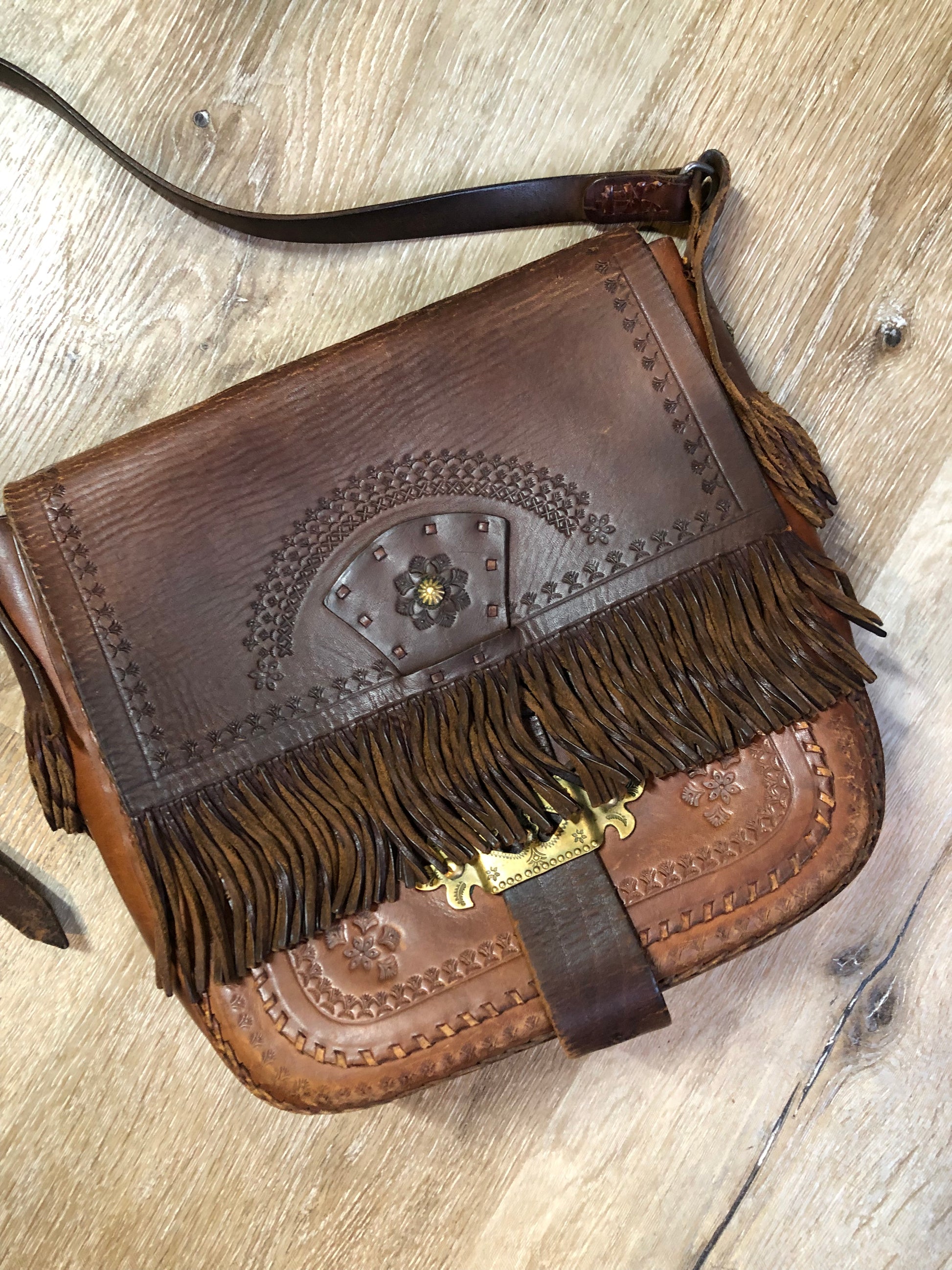 Vintage full grain brown leather crossbody bag with leather fringe, hand tooled designs, brass hardware, flap closure, two interior compartments and adjustable shoulder strap.  Bag is scented with patchouli - Kingspier Vintage