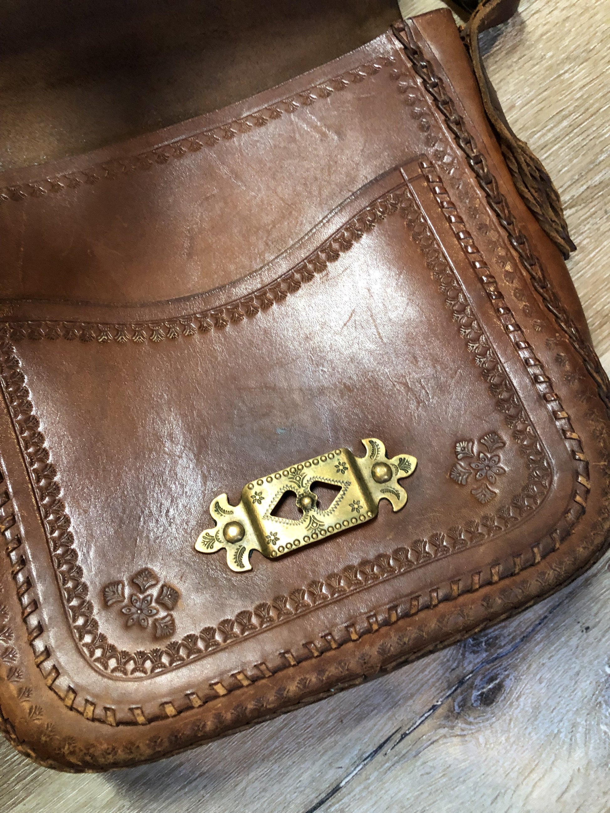 Vintage full grain brown leather crossbody bag with leather fringe, hand tooled designs, brass hardware, flap closure, two interior compartments and adjustable shoulder strap.  Bag is scented with patchouli - Kingspier Vintage