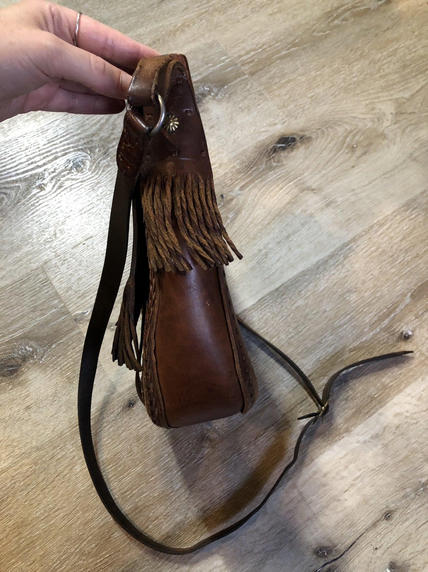 Vintage full grain brown leather crossbody bag with leather fringe, hand tooled designs, brass hardware, flap closure, two interior compartments and adjustable shoulder strap. Bag is scented with patchouli - Kingspier Vintage