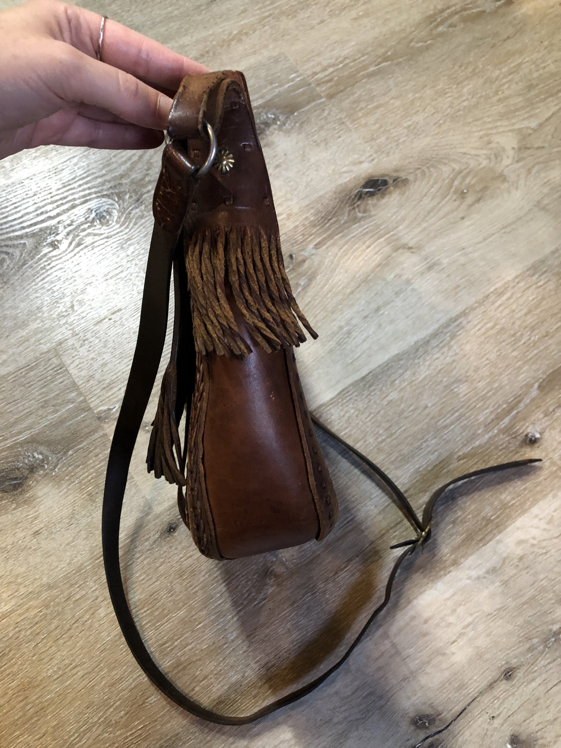 Vintage full grain brown leather crossbody bag with leather fringe, hand tooled designs, brass hardware, flap closure, two interior compartments and adjustable shoulder strap.  Bag is scented with patchouli - Kingspier Vintage