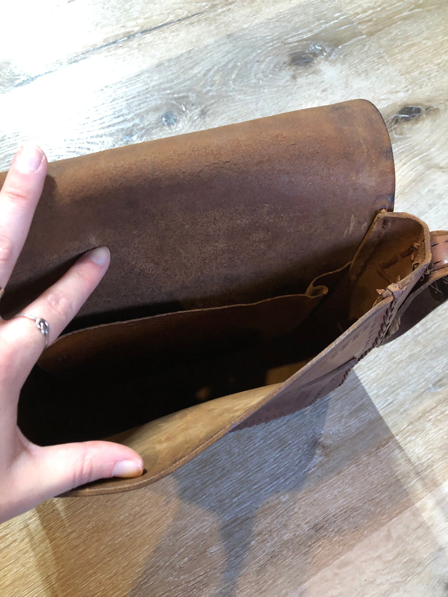 Vintage full grain brown leather crossbody bag with leather fringe, hand tooled designs, brass hardware, flap closure, two interior compartments and adjustable shoulder strap. Bag is scented with patchouli - Kingspier Vintage
