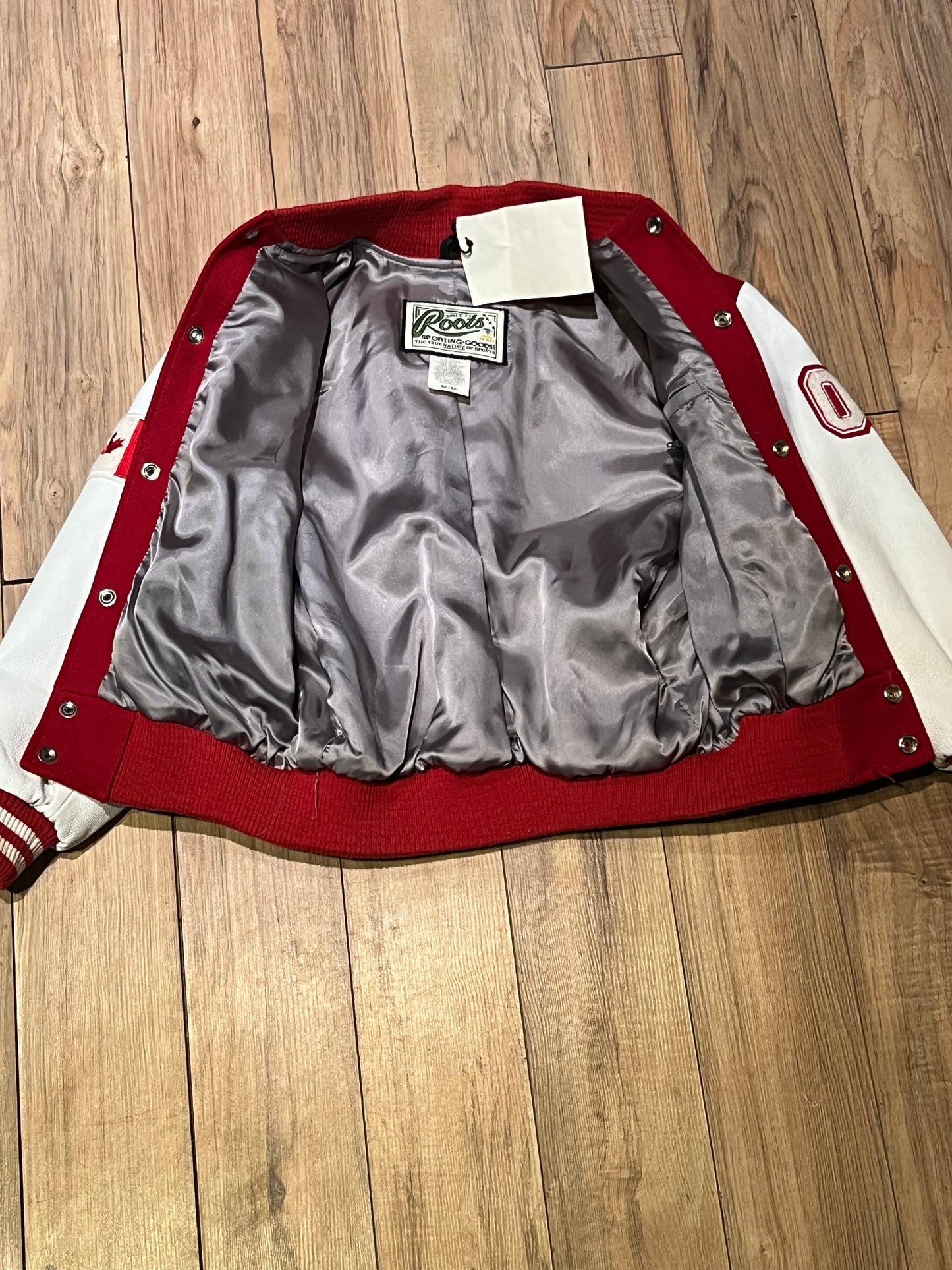 Roots Athletics circa 2000 red and white varsity jacket with wool blend body, leather sleeves, snap closures, two front slash pockets, “R” patch on the chest, Canada flag patch on the arm, “00” patch on the arm and “Canada” written across the back.
Made in Canada
Size Youth Medium