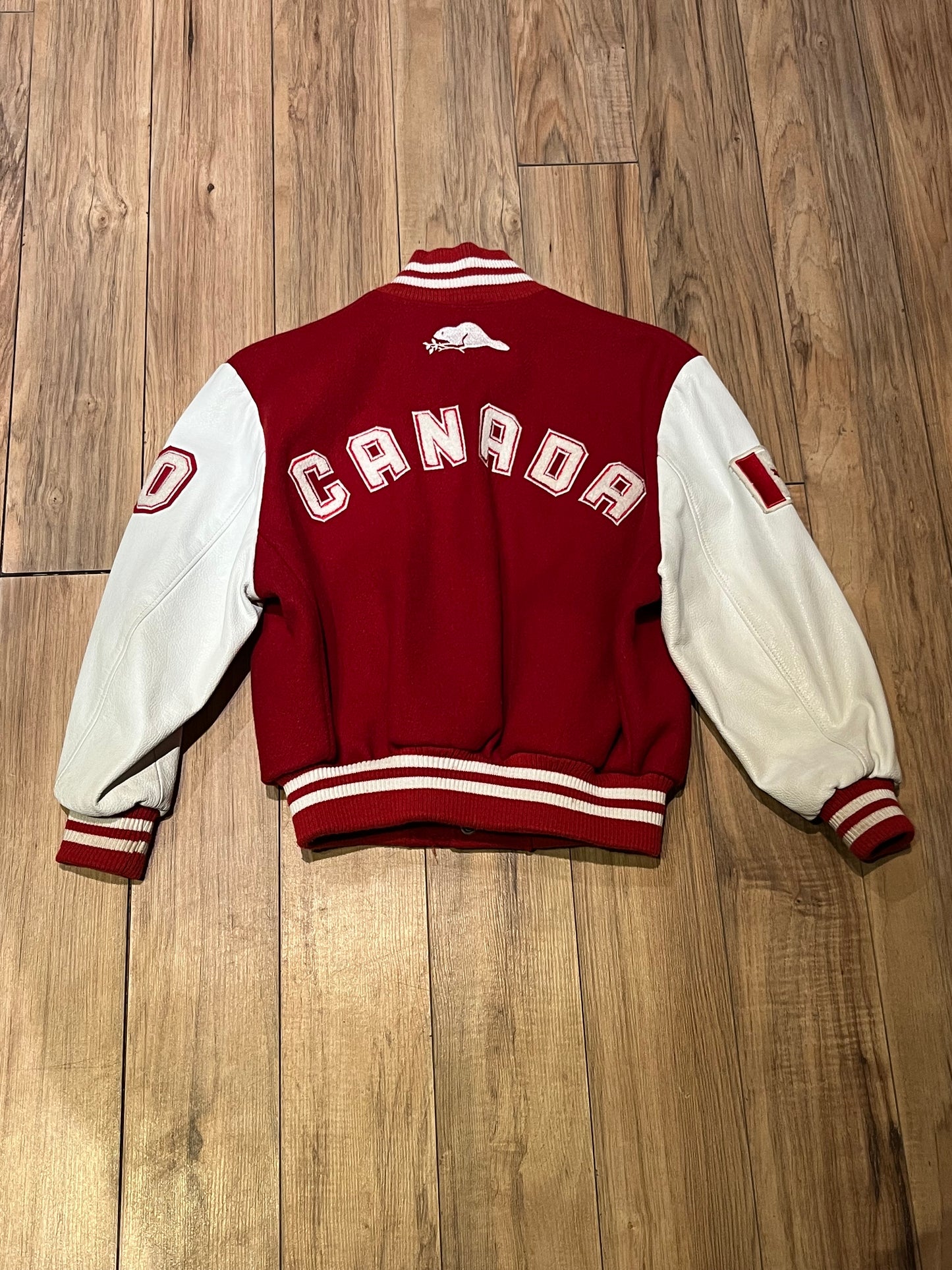 Roots Athletics circa 2000 red and white varsity jacket with wool blend body, leather sleeves, snap closures, two front slash pockets, “R” patch on the chest, Canada flag patch on the arm, “00” patch on the arm and “Canada” written across the back.
Made in Canada
Size Youth Medium