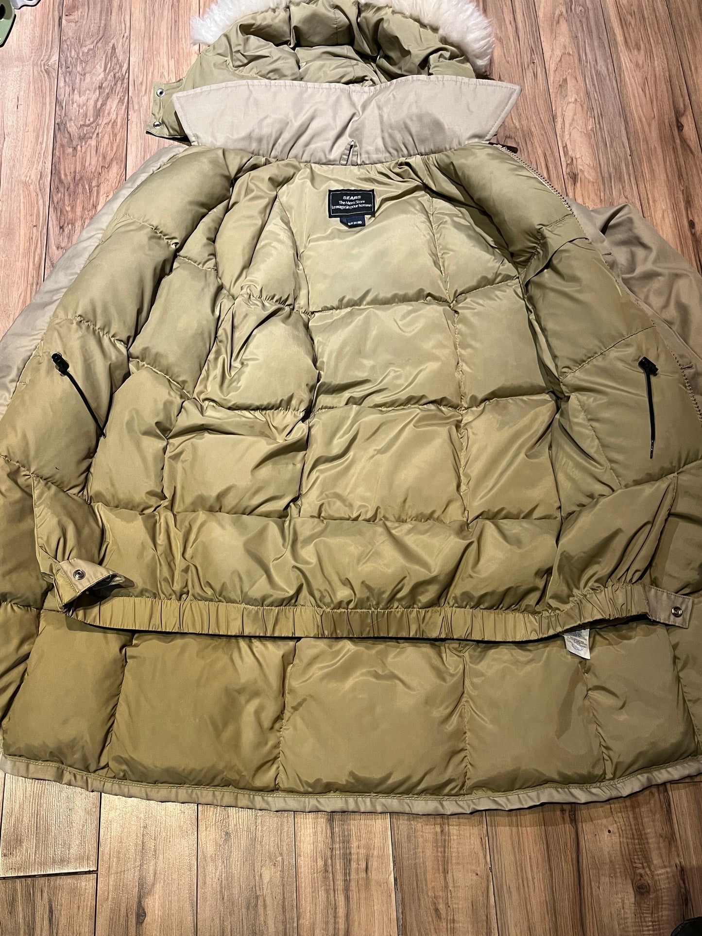 Vintage Sears “The Mens Store” beige down-filled parka (60% duck down/ 40% waterfowl feather) with cotton/nylon blend shell, zipper and button closures, two hand-warmer pockets, two flap pockets, two inside zip pockets, hood with fur trim and storm cuffs.
Made in Canada
Size Small 34-36