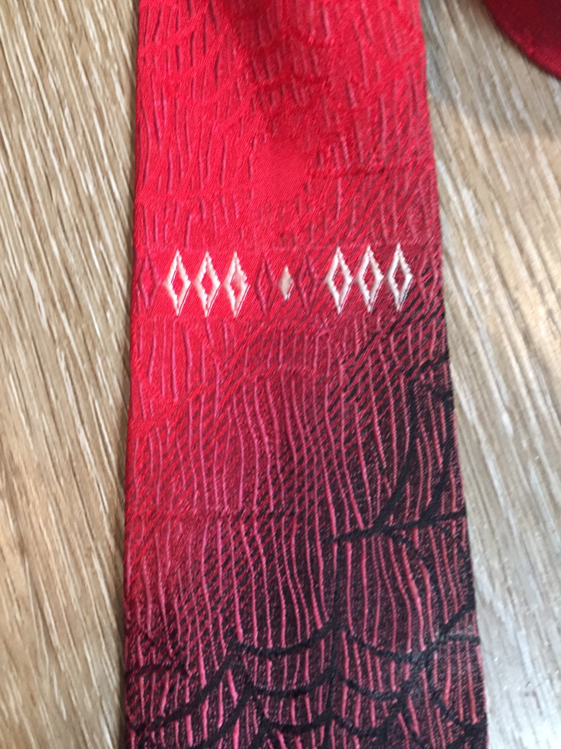 Kingspier Vintage - Abbey red tie with black spider web motif. Fibres unknown.
Length: 55”
Width: 2.5” 
This tie is in excellent condition.