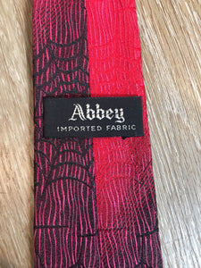 Kingspier Vintage - Abbey red tie with black spider web motif. Fibres unknown.

Length: 55”
Width: 2.5” 

This tie is in excellent condition.