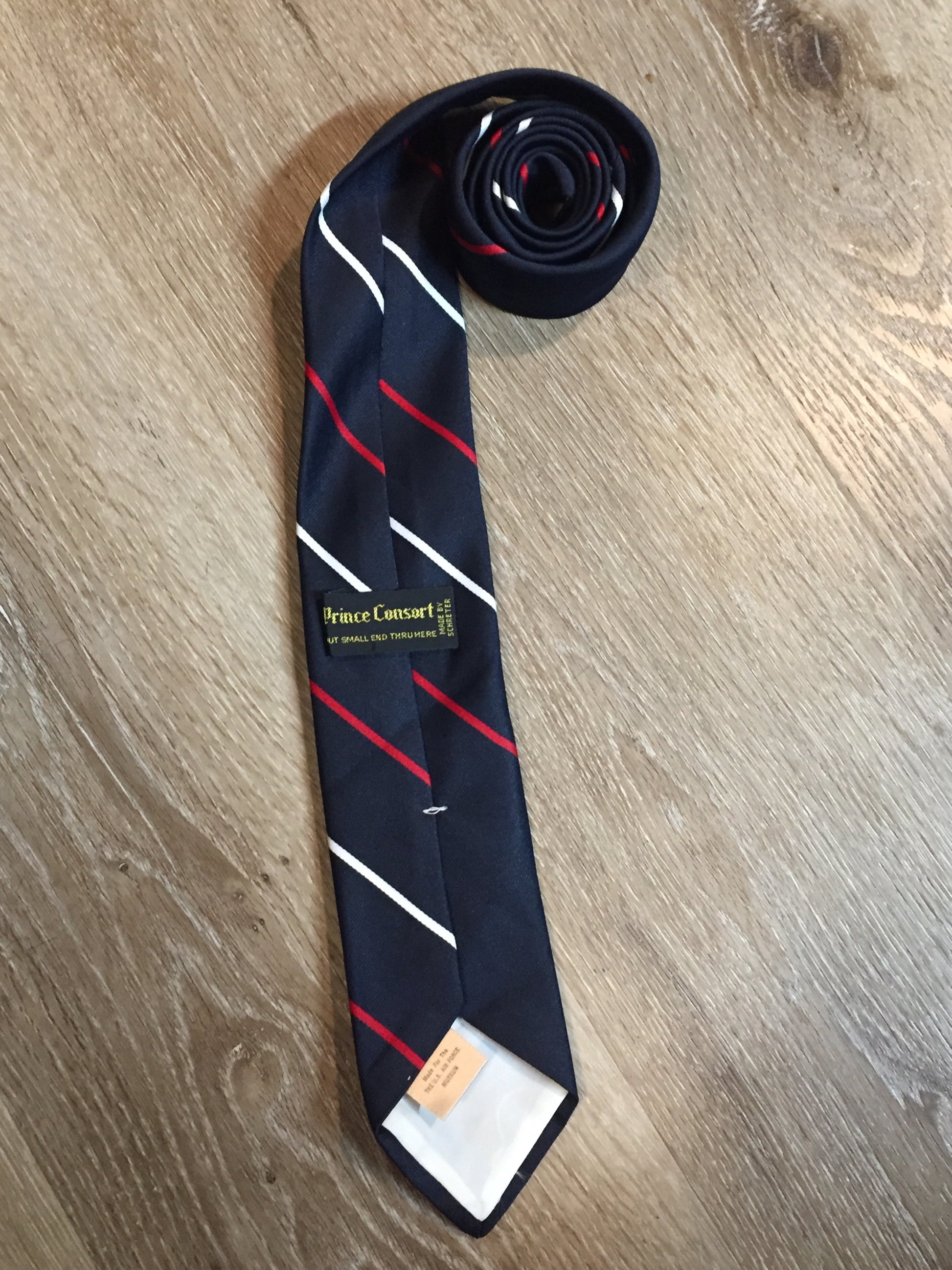 Kingspier Vintage - Prince Consort 100% polyester tie in navy with white and red stripes and a small jet illustration at the bottom center of the tie. Made for the U.S. airforce.
 
Length: 58.25” 
Width: 3” 
This tie is in excellent condition.