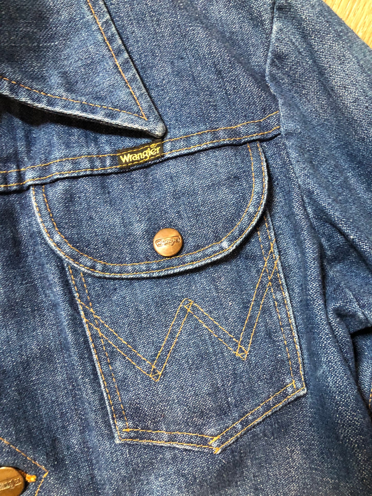 Vintage Wrangler medium wash denim jacket with button closures, two flap pockets on the chest and two hand warmer pockets in the front. 100% cotton, made in Canada, size 32 - Kingspier Vintage