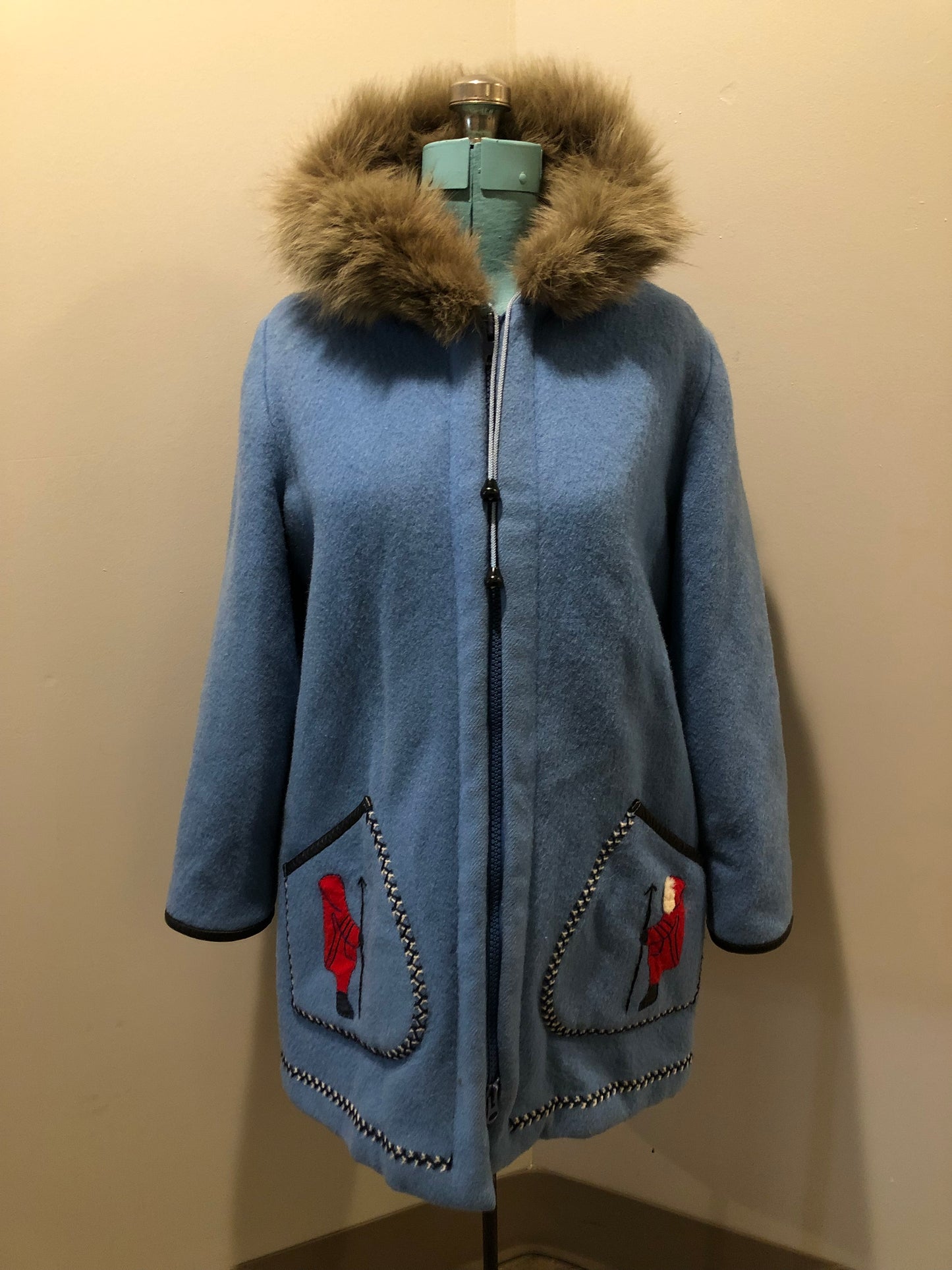 Vintage James Bay 100% pure wool northern parka in sky blue. This parka features a fur trimmed hood, zipper closure, patch pockets, quilted lining, storm cuffs, leather trim, embroidery details and a northern life design in felt applique. Made in Canada. Size 12 - Kingspier Vintage