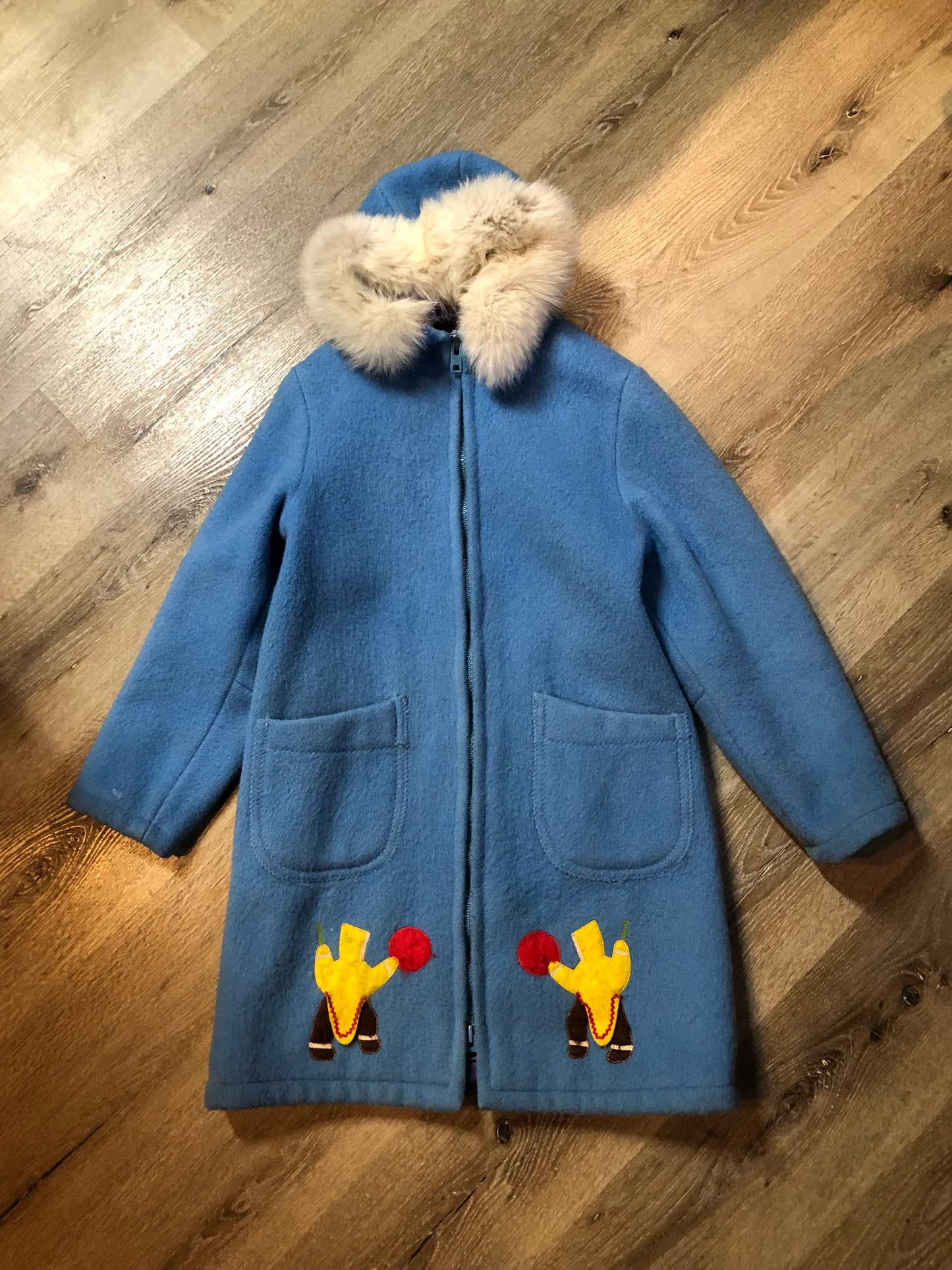 Vintage Hudson’s Bay Company 100% pure wool northern parka in sky blue. This parka features a fur trimmed hood, zipper closure, patch pockets, purple satin lining and a drumming and dance design in felt applique. Made in Canada by the Inuvik Parka Company - Kingspier Vintage