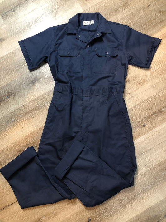 Kingspier Vintage - Vintage Deadstock Anchor Textiles short sleeve navy coveralls with snap closures, elastic waistband, flap pockets on the chest, slash pockets in the front and patch pockets in the back. Union made in Canada. Size medium/ large.