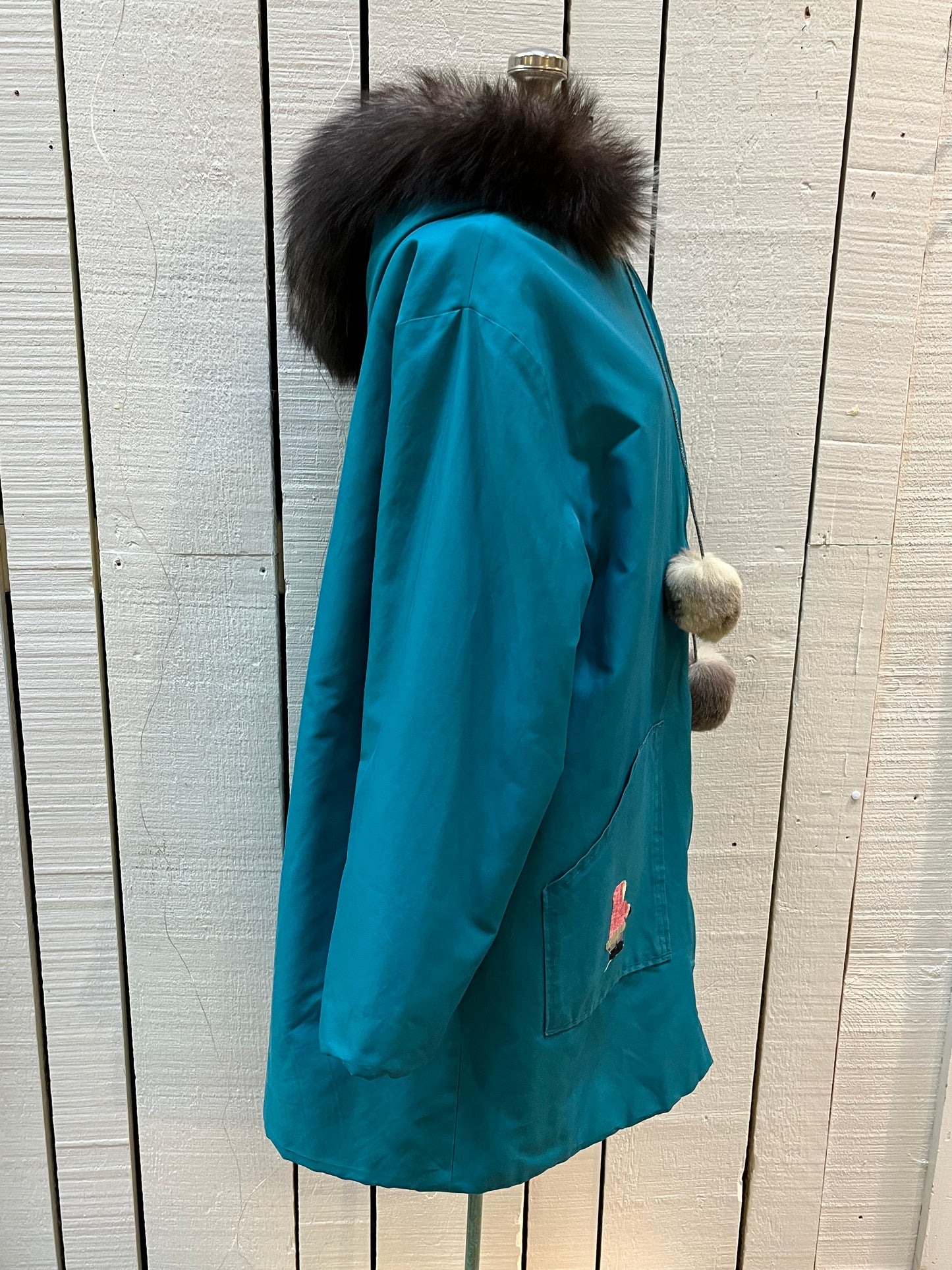 Vintage teal northern parka with fur trimmed hood, fur pom poms, zipper closure, patch pockets in the front and hand embroidered details.
Chest 46”