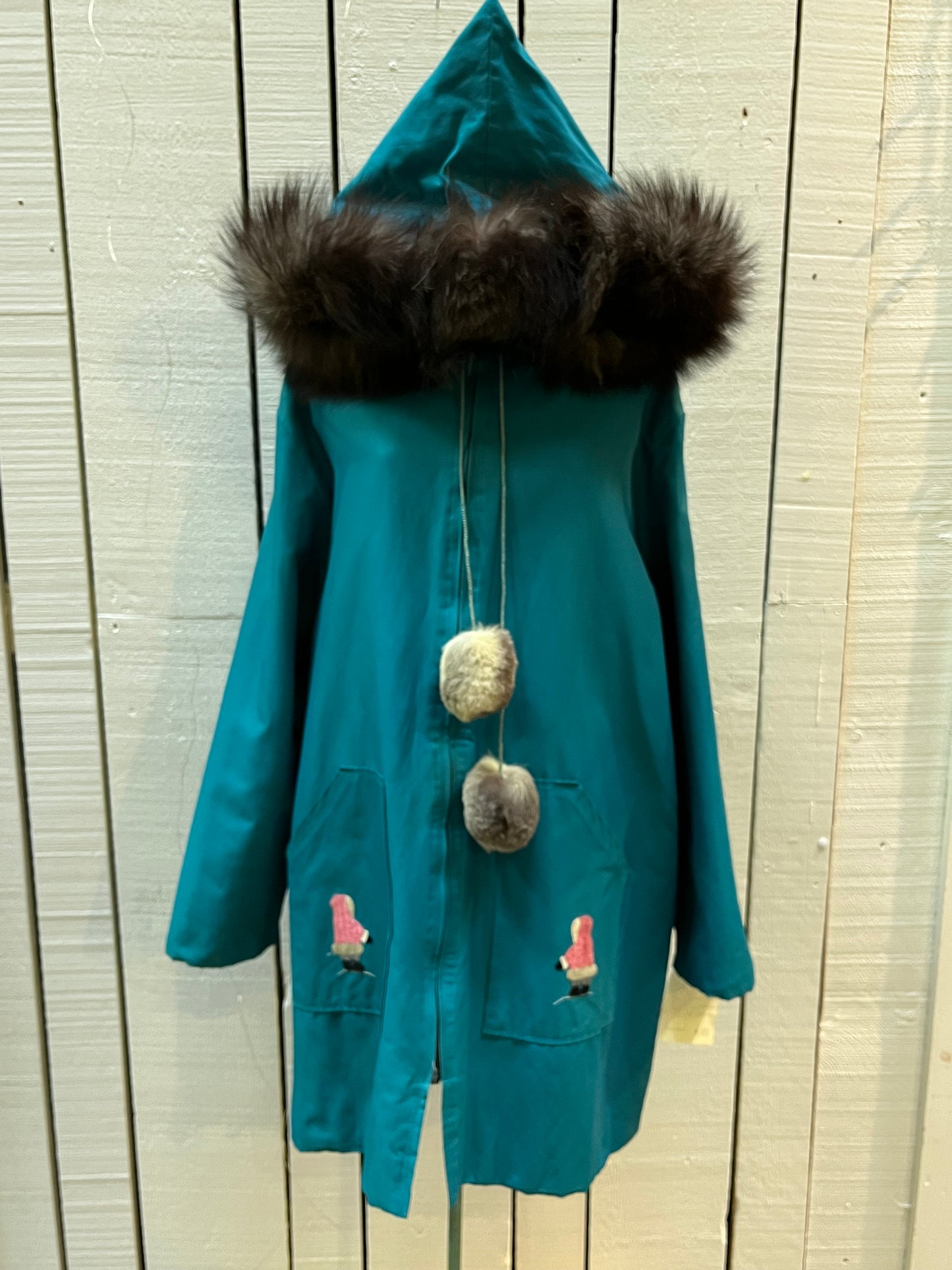 Vintage teal northern parka with fur trimmed hood, fur pom poms, zipper closure, patch pockets in the front and hand embroidered details.
Chest 46”