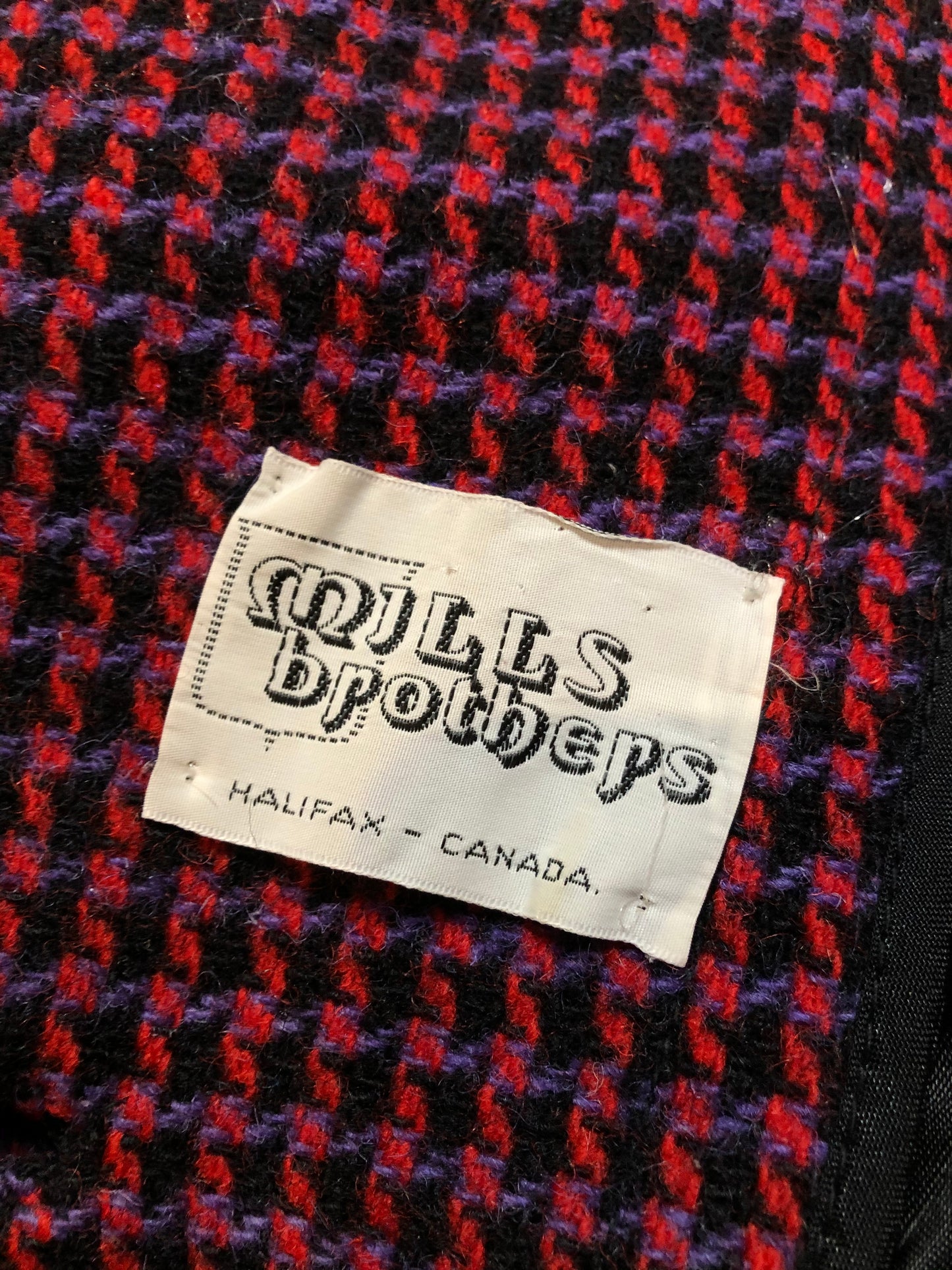 Kingspier Vintage - Mills Brothers red, black and blue houndstooth wool coat. The colours in the houndstooth come together to make a deep purple. This coat features button closures, vertical pockets, knit inner cuffs, a satin lining and zip out genuine chamois inner- lining. Made in Canada. Size medium/ large.