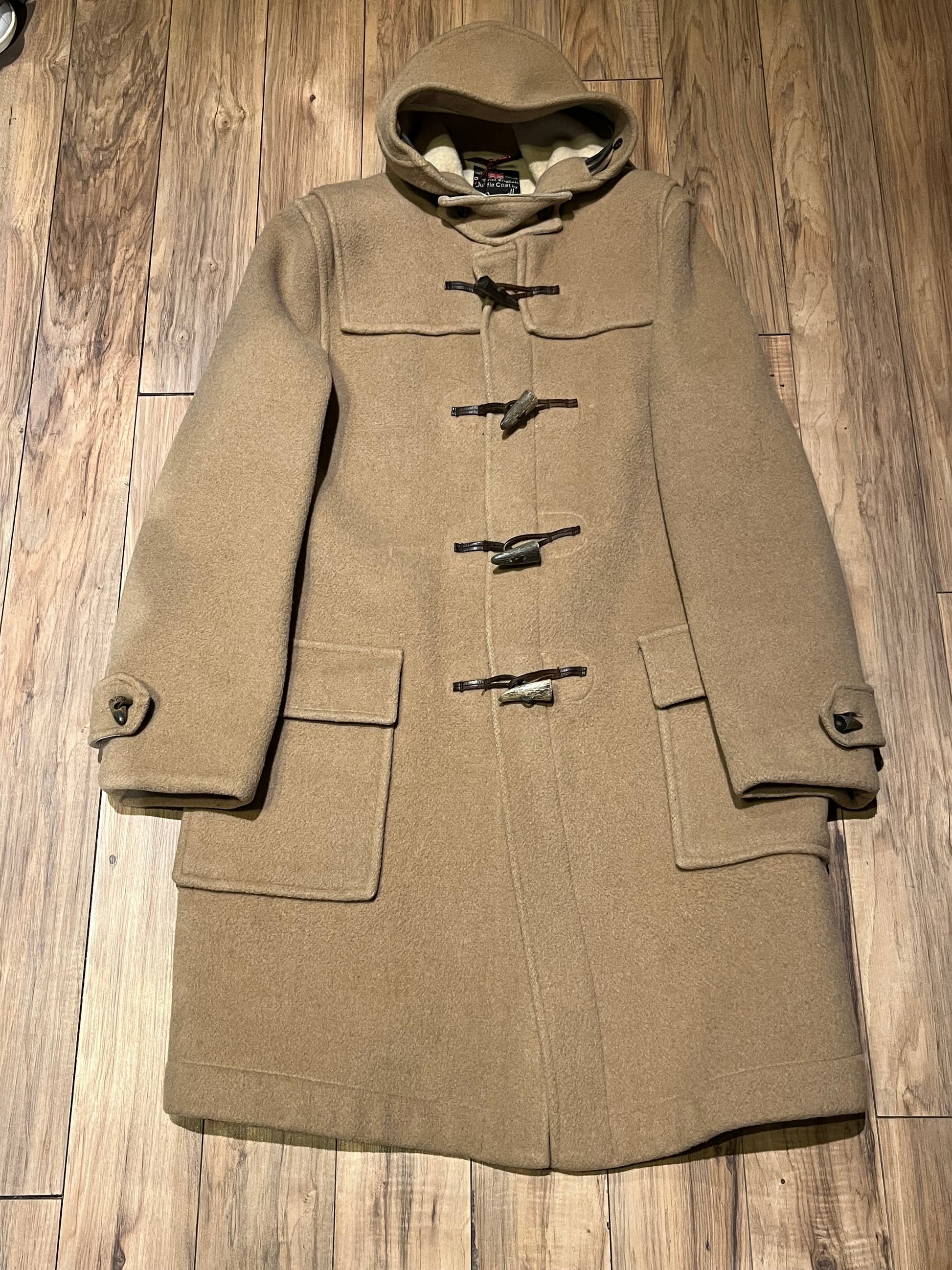 Vintage Gloverall tan duffle coat, with zipper and horn toggle closures, hood and two flap pockets.
80% wool/ 20% polyester
Made in England
Size 52