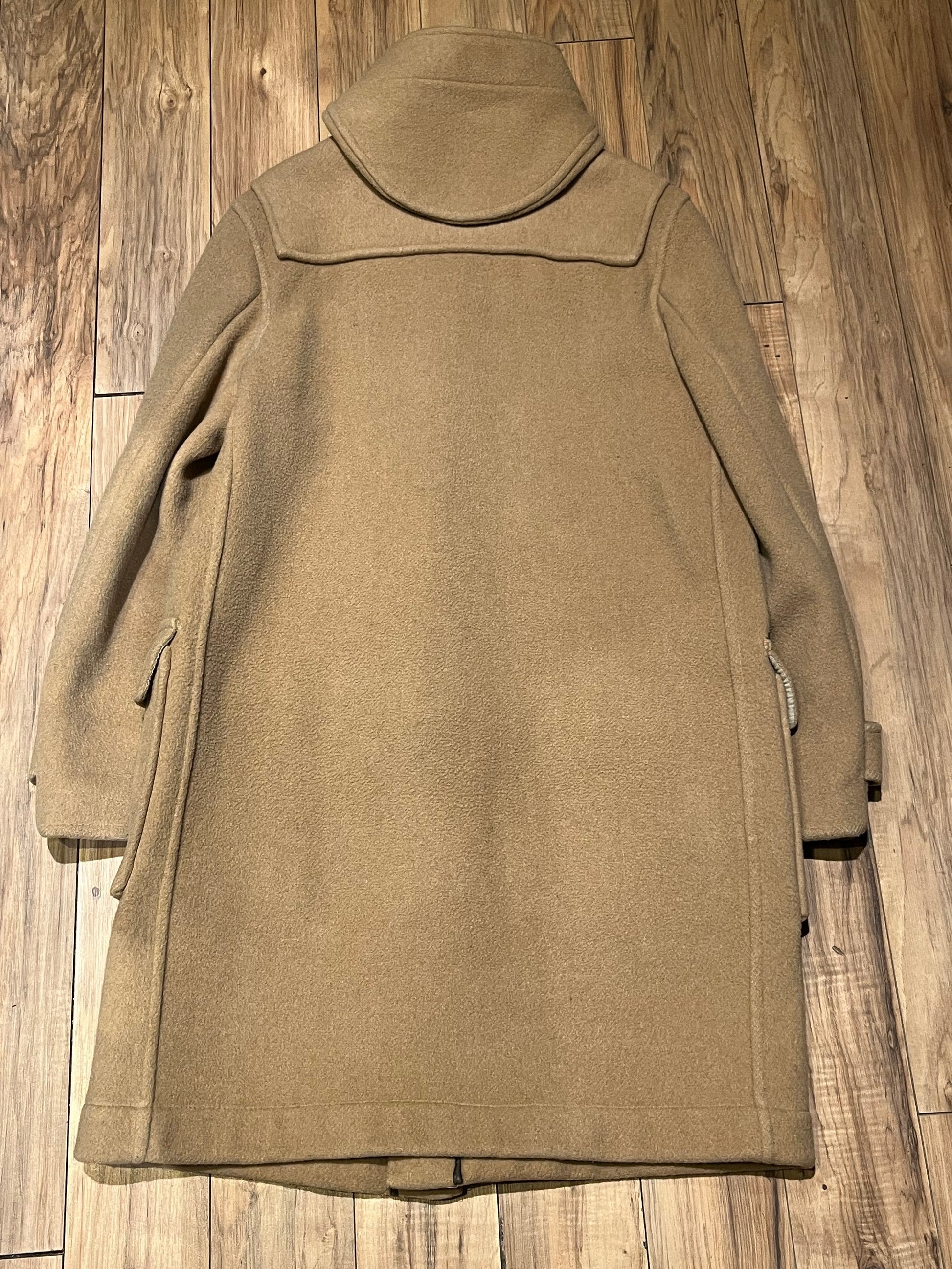 Vintage Gloverall tan duffle coat, with zipper and horn toggle closures, hood and two flap pockets.
80% wool/ 20% polyester
Made in England
Size 52