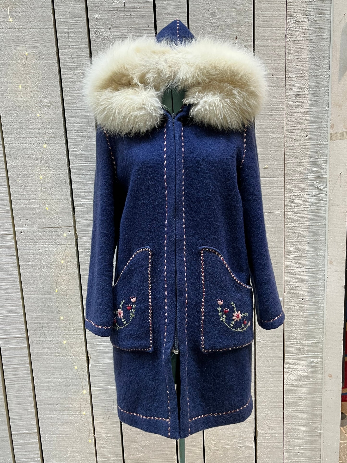 Vintage blue wool northern parka with zipper closures, two patch pockets, white fur trimmed hood, hand embroidered flower details and an embroidered bird on the back.
Chest 42”