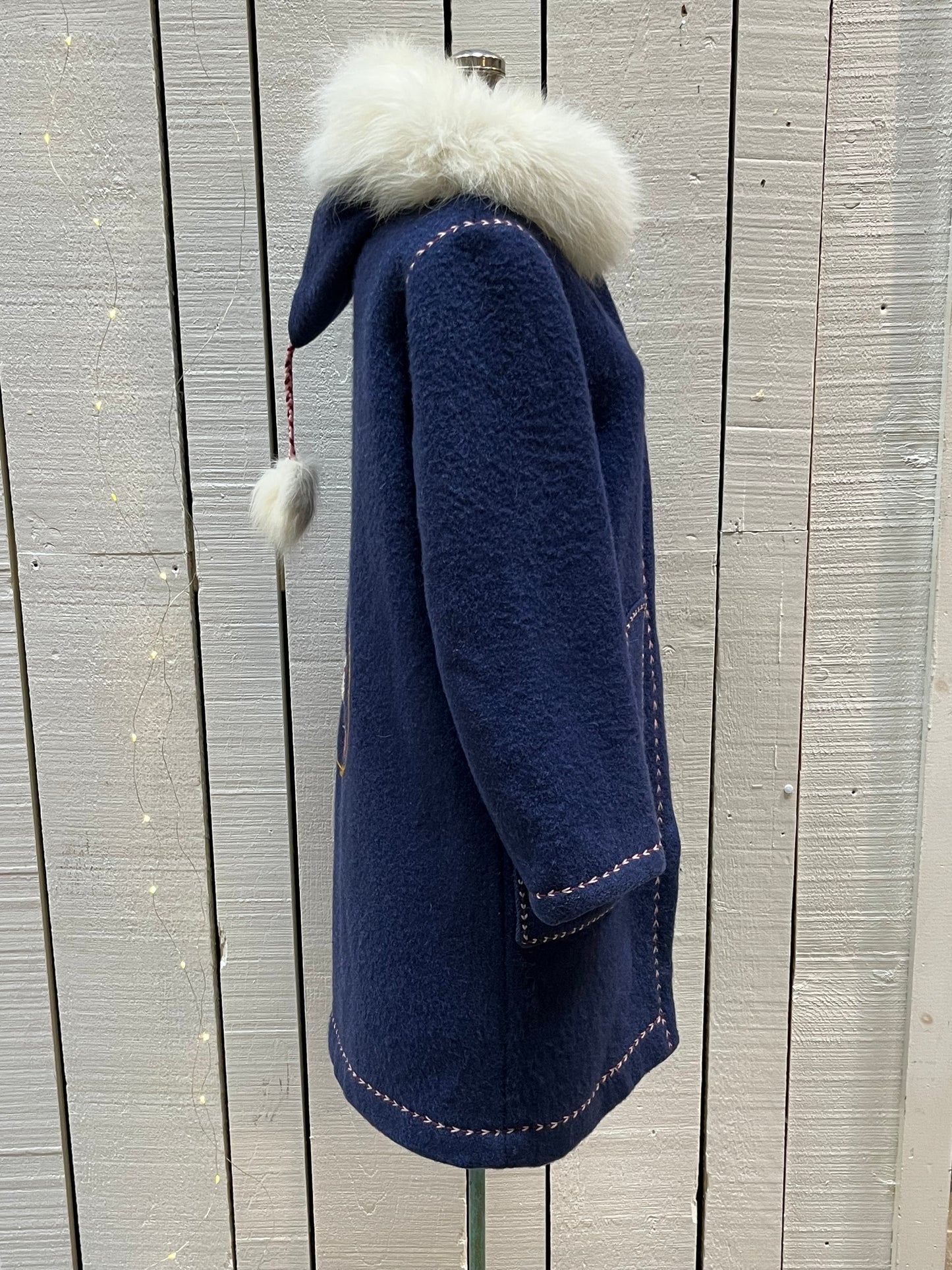 Vintage blue wool northern parka with zipper closures, two patch pockets, white fur trimmed hood, hand embroidered flower details and an embroidered bird on the back.
Chest 42”
