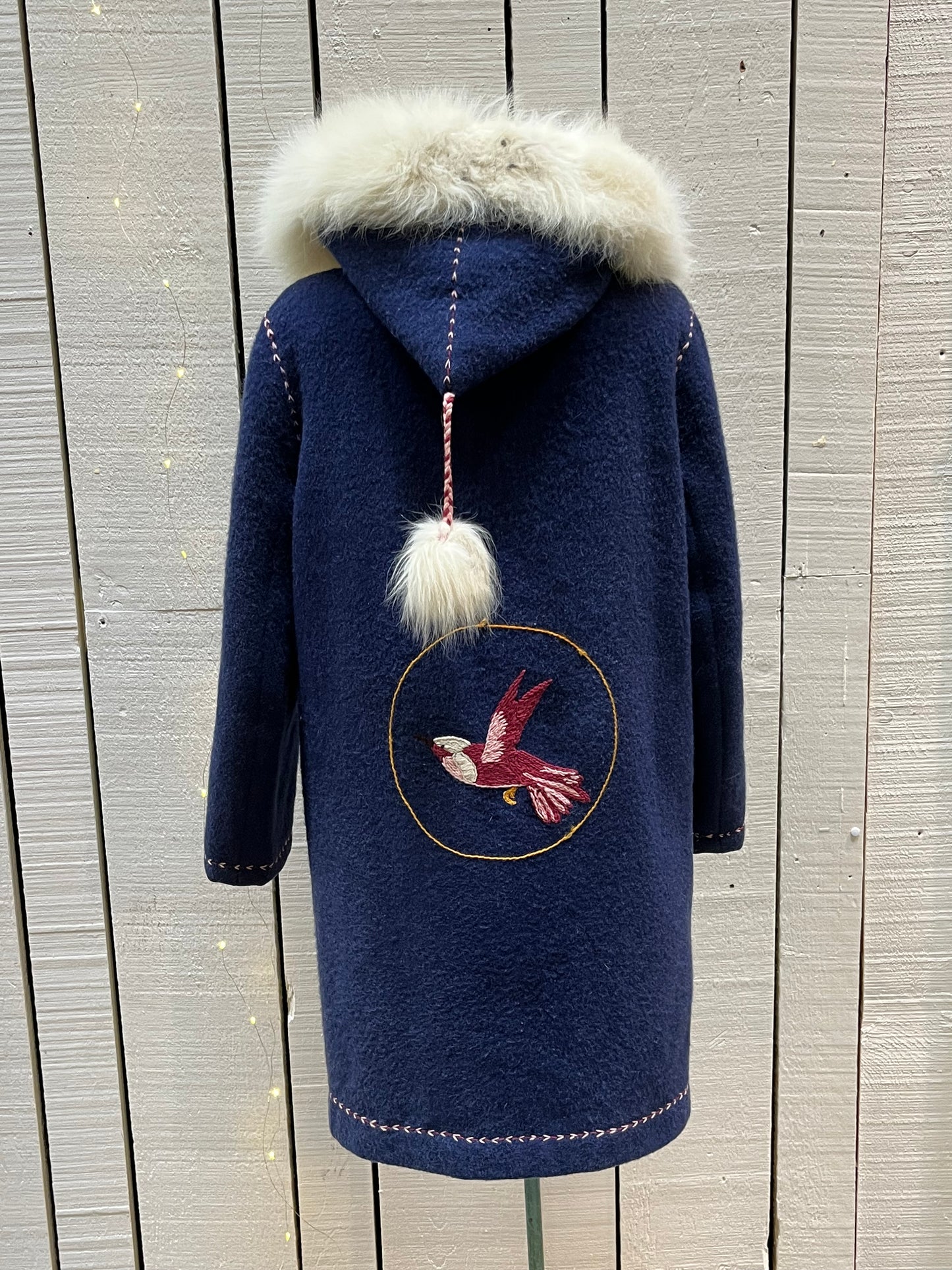 Vintage blue wool northern parka with zipper closures, two patch pockets, white fur trimmed hood, hand embroidered flower details and an embroidered bird on the back.
Chest 42”