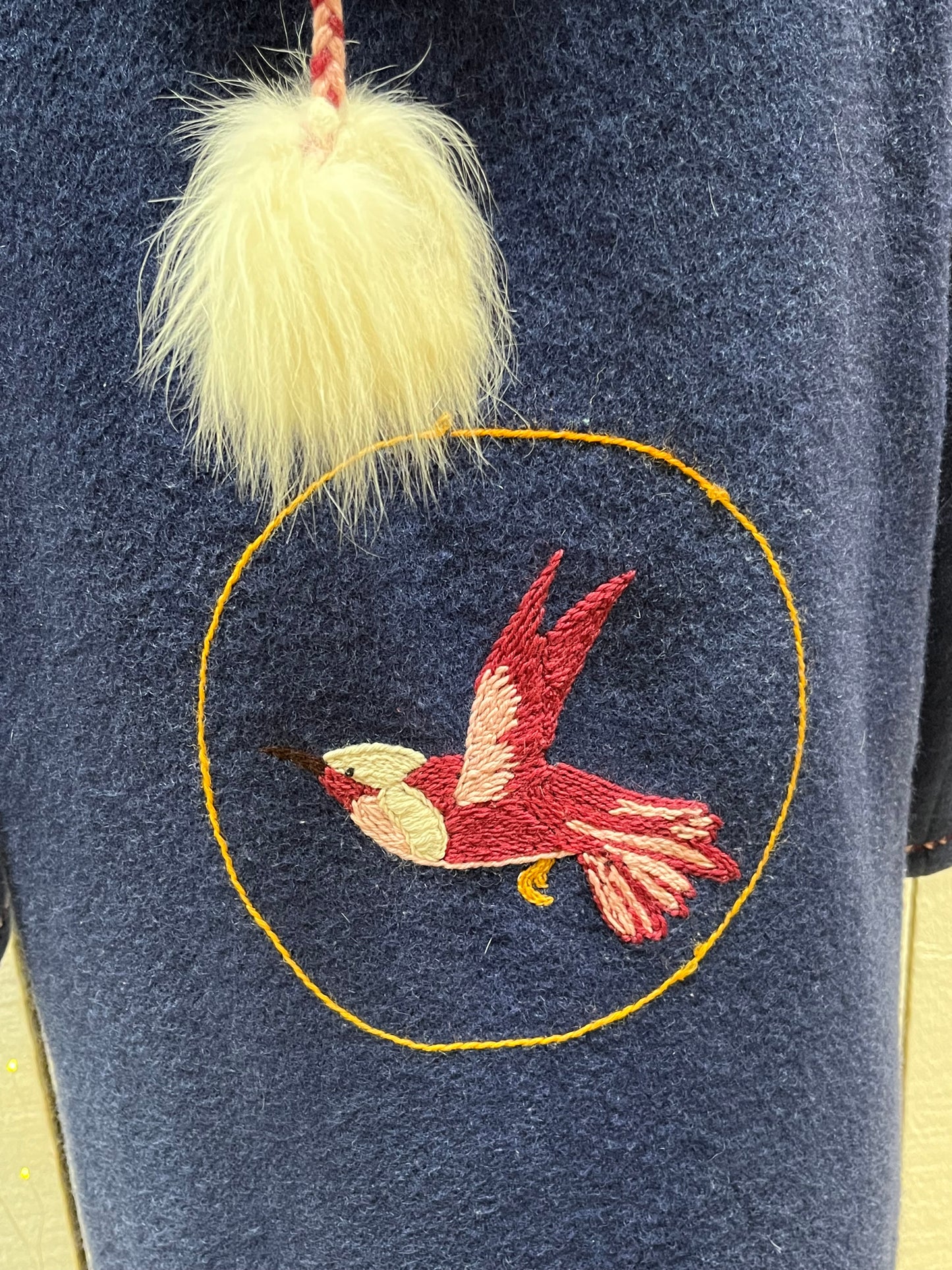 Vintage blue wool northern parka with zipper closures, two patch pockets, white fur trimmed hood, hand embroidered flower details and an embroidered bird on the back.
Chest 42”
