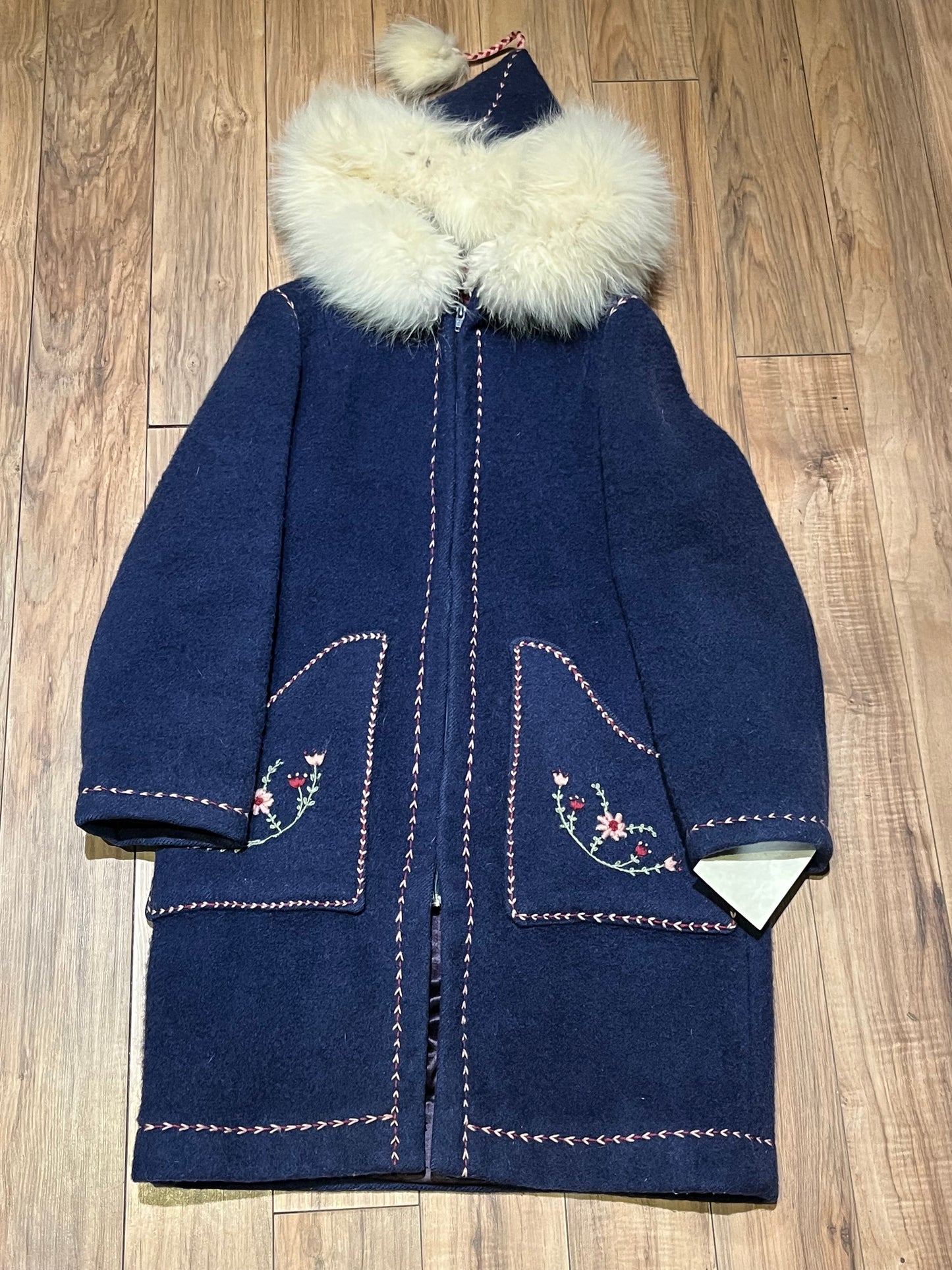 Vintage blue wool northern parka with zipper closures, two patch pockets, white fur trimmed hood, hand embroidered flower details and an embroidered bird on the back.
Chest 42”