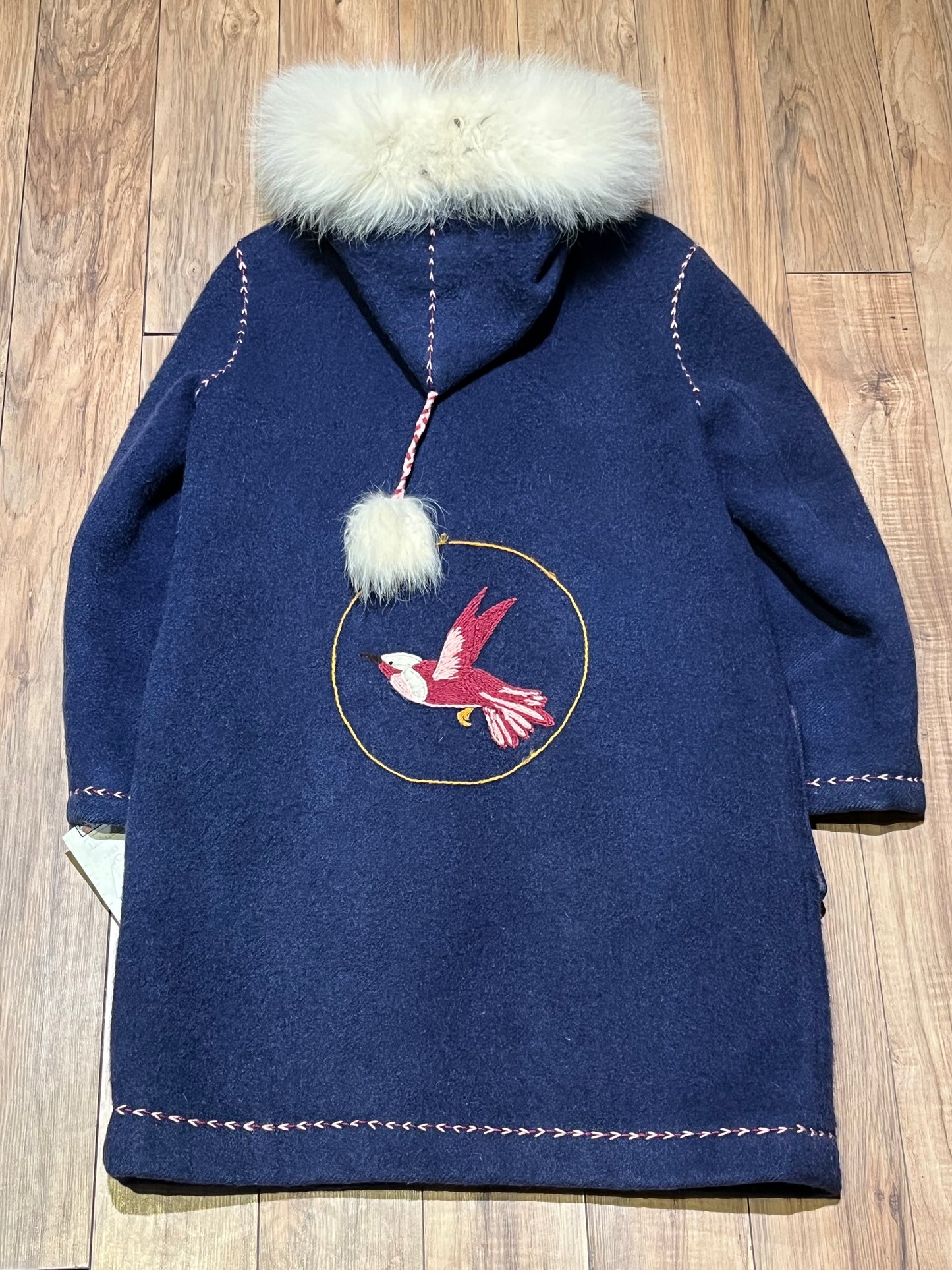 Vintage blue wool northern parka with zipper closures, two patch pockets, white fur trimmed hood, hand embroidered flower details and an embroidered bird on the back.
Chest 42”