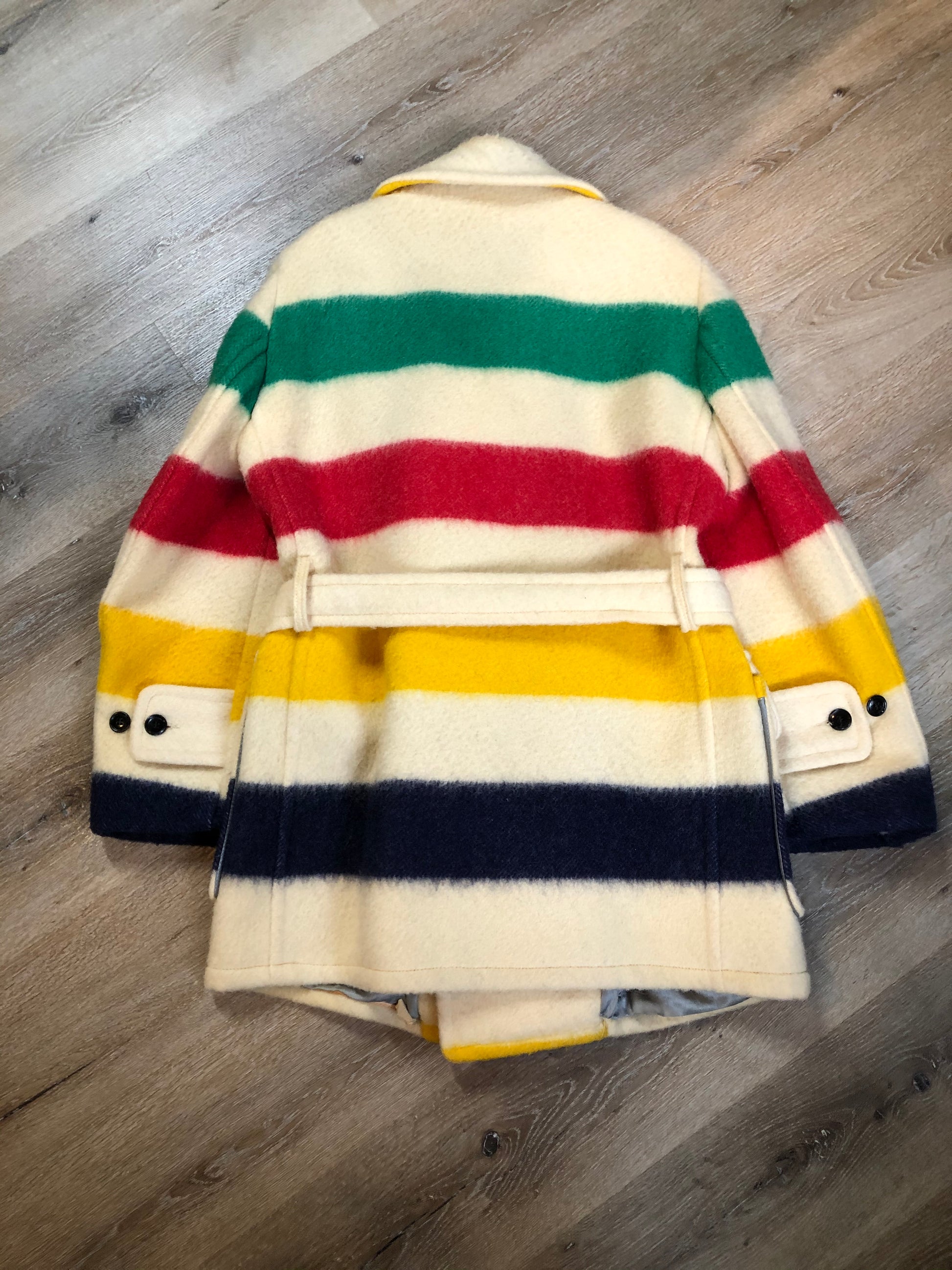 Kingspier Vintage - Genuine Hudson’s Bay Company point blanket coat in the iconic multistripe colours. The coat features flap pockets and hand warmer pockets, double breasted button closures and belt. Made in Canada. Men’s size 46.
