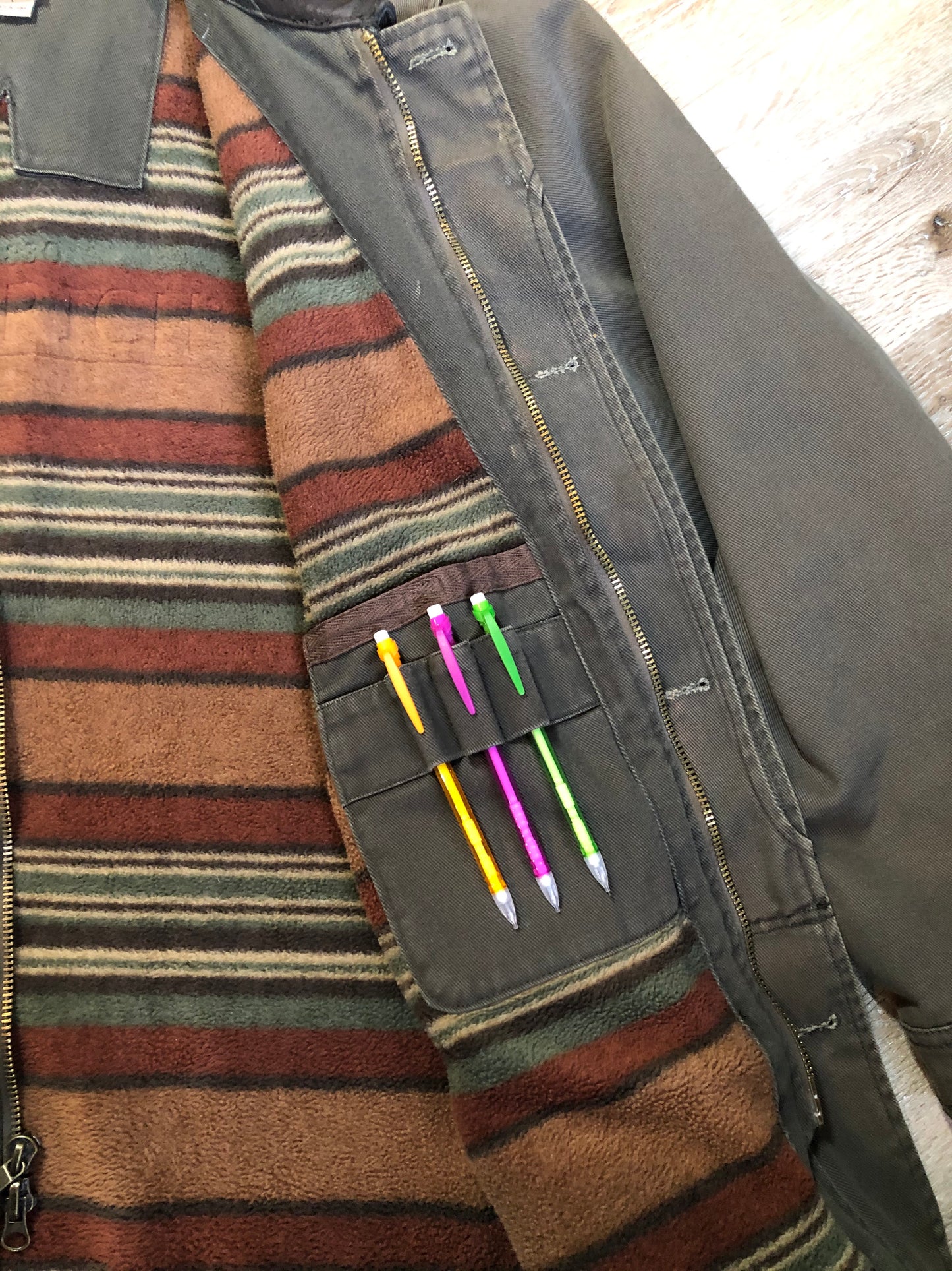 Kingspier Vintage - Woolrich olive green chore jacket features suede collar, flap pockets, hand warmer pockets, zipper and button closures, inside autumn colour striped fleece lining and inside pocket with pencil/ small tool holders. Men’s large.