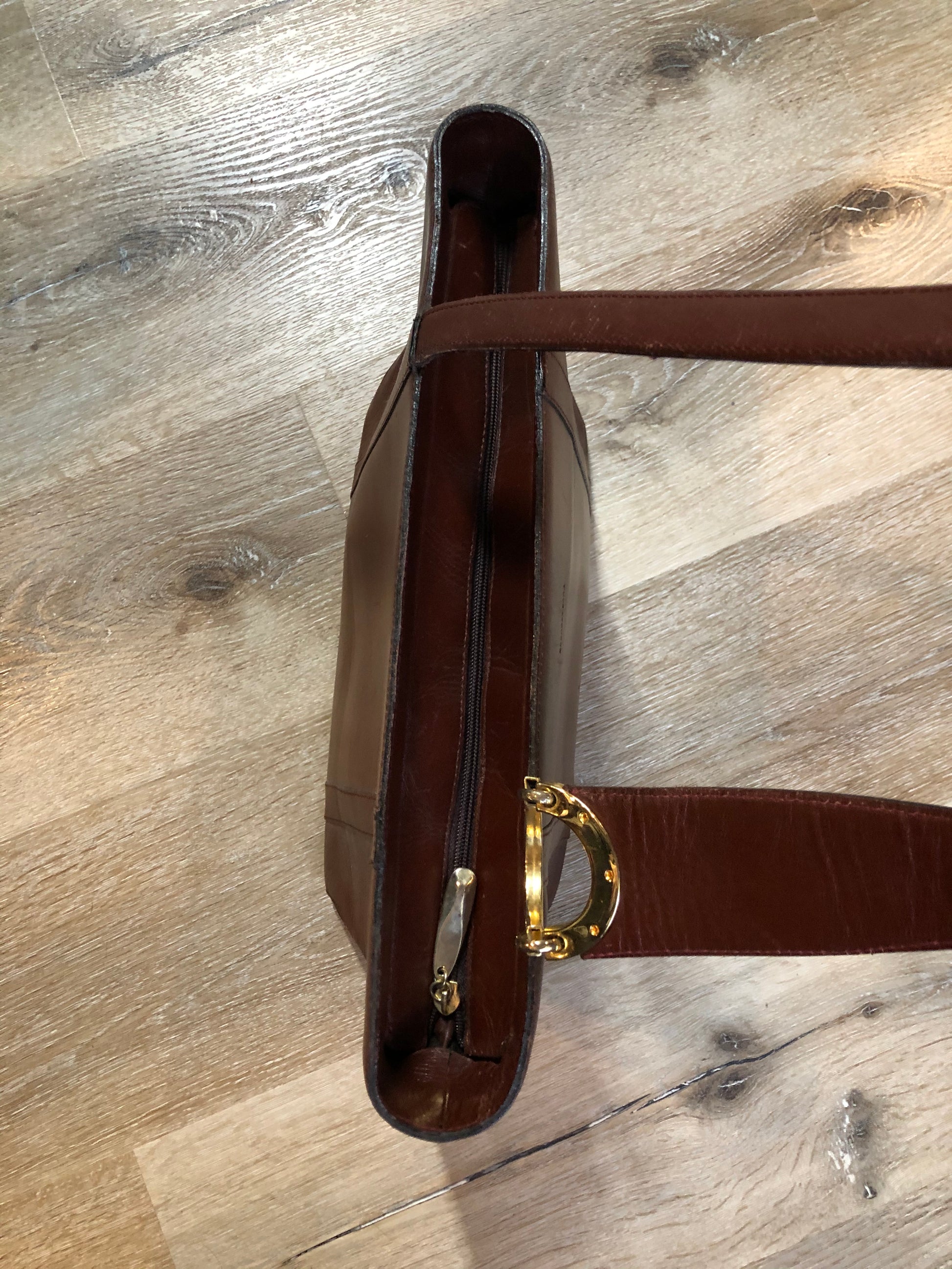 Kingspier Vintage - Georges Sara brown leather handbag with unique brass hardware, zipper top closure with three compartments inside. 
Length - 11.5”
Width - .5”
Height - 9”
Strap - 30”
This purse is in excellent condition.