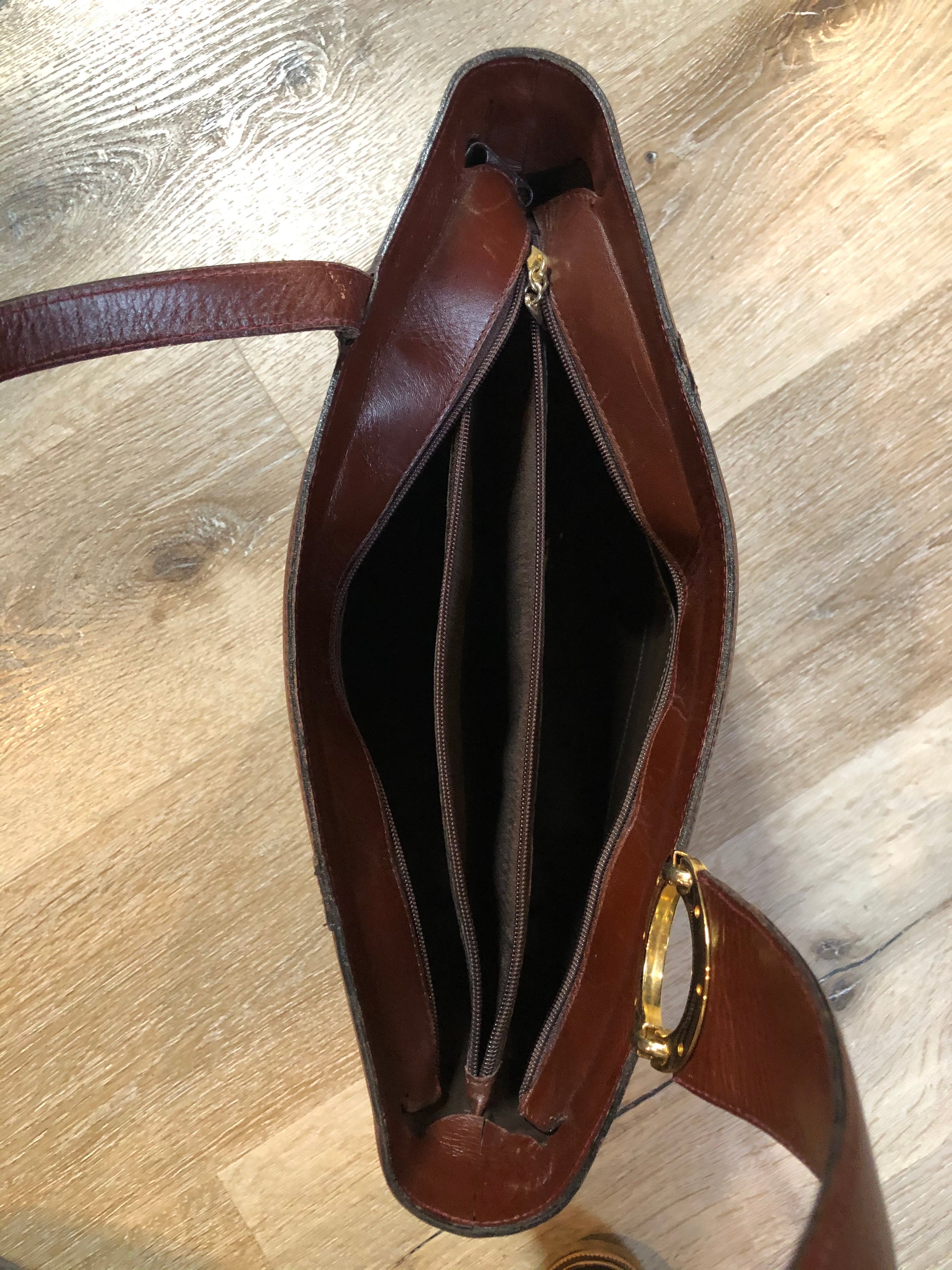 Kingspier Vintage - Georges Sara brown leather handbag with unique brass hardware, zipper top closure with three compartments inside. 
Length - 11.5”
Width - .5”
Height - 9”
Strap - 30”
This purse is in excellent condition.