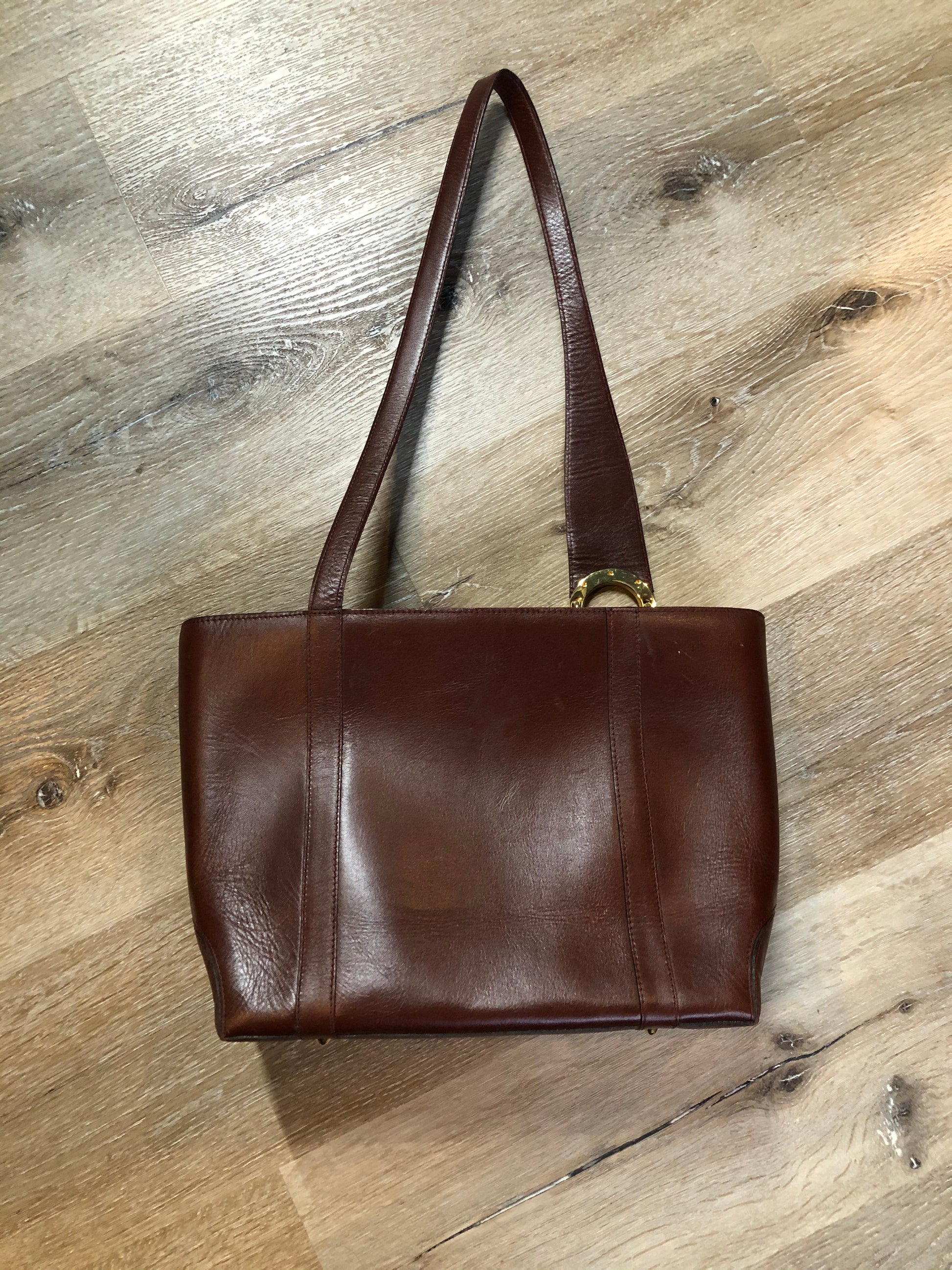 Kingspier Vintage - Georges Sara brown leather handbag with unique brass hardware, zipper top closure with three compartments inside. 
Length - 11.5”
Width - .5”
Height - 9”
Strap - 30”
This purse is in excellent condition.