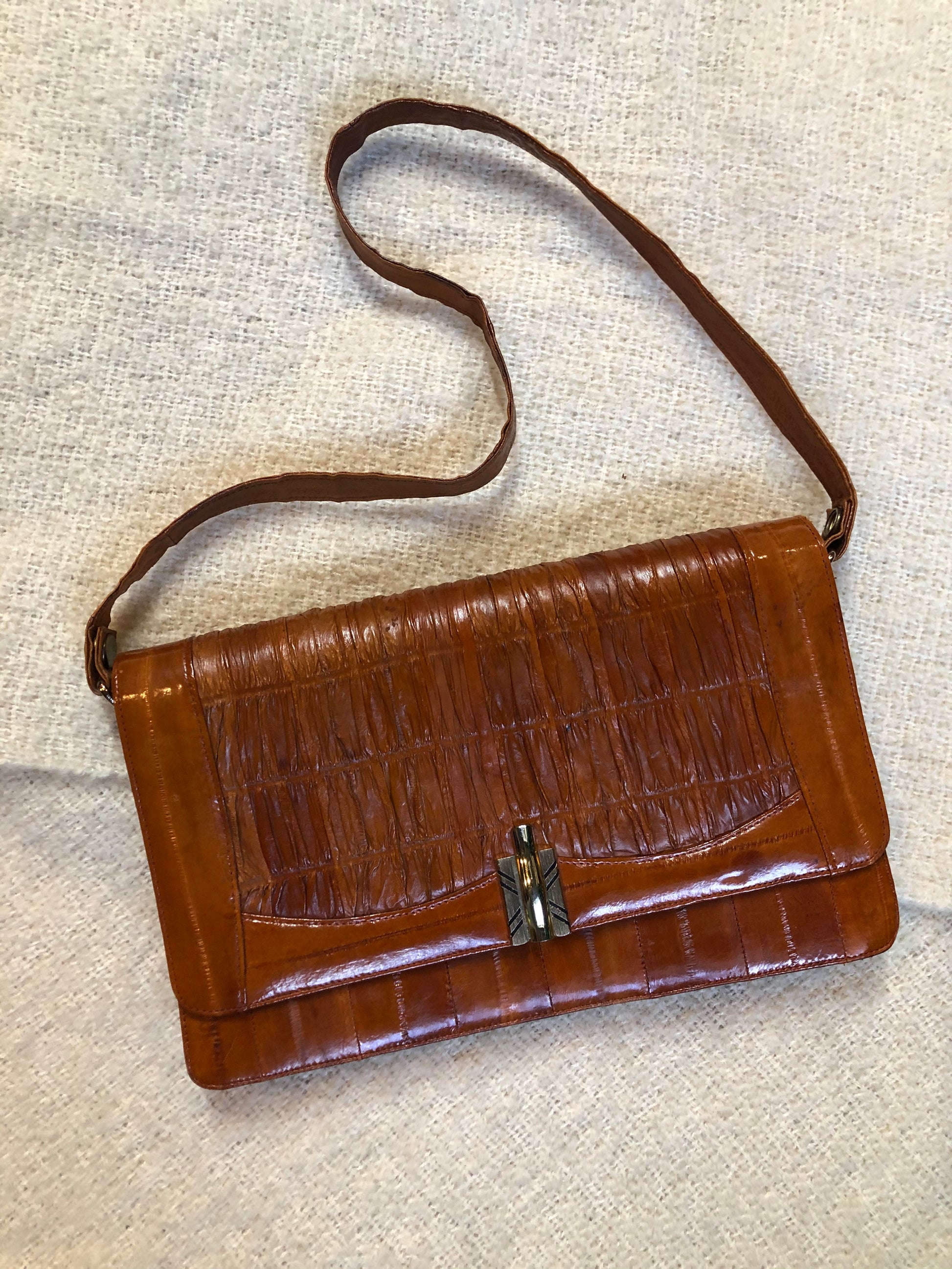 Kingspier Vintage - Vintage satchel in very soft caramel colour leather with gathered leather details, a unique front clasp, brass hardware and three inside compartments. 
Length - 12”
Width - 1”
Height - 7.5”
Strap - 30.5”
This purse is in excellent condition.