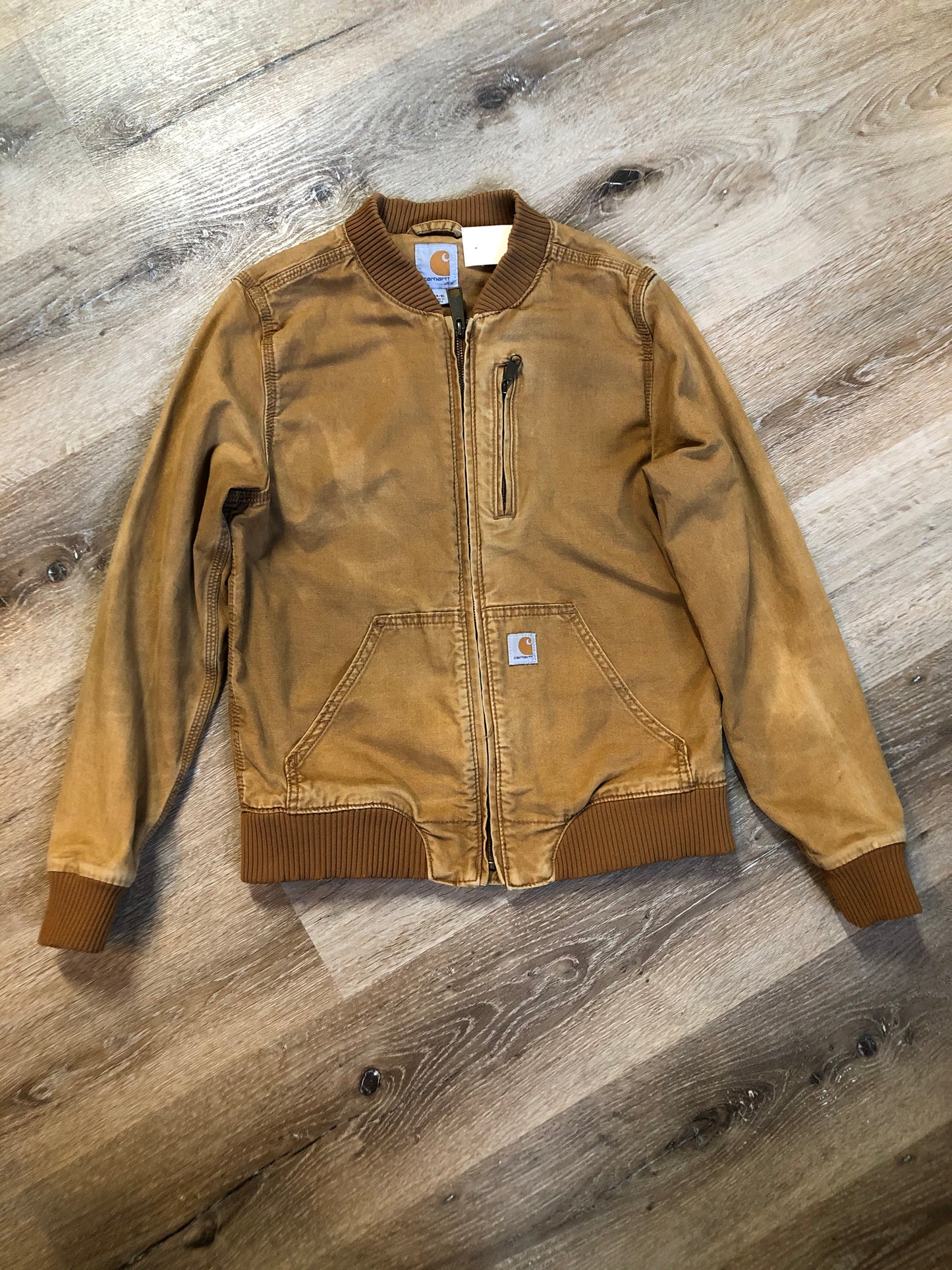 Kingspier Vintage - Carhartt tan bomber jacket with zipper closure, pockets, vertical zip pocket on chest, inside pocket and a lightweight lining. Women’s small.