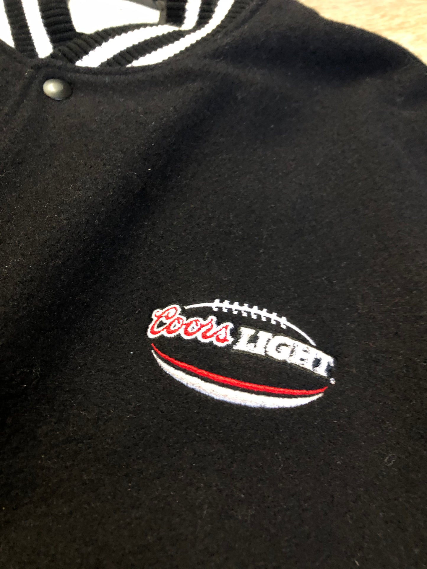 Kingspier Vintage - Coors Light black wool blend varsity jacket with black leather arms, knit trim, slash pockets, snap closure and a quilted lining. Men’s XL.