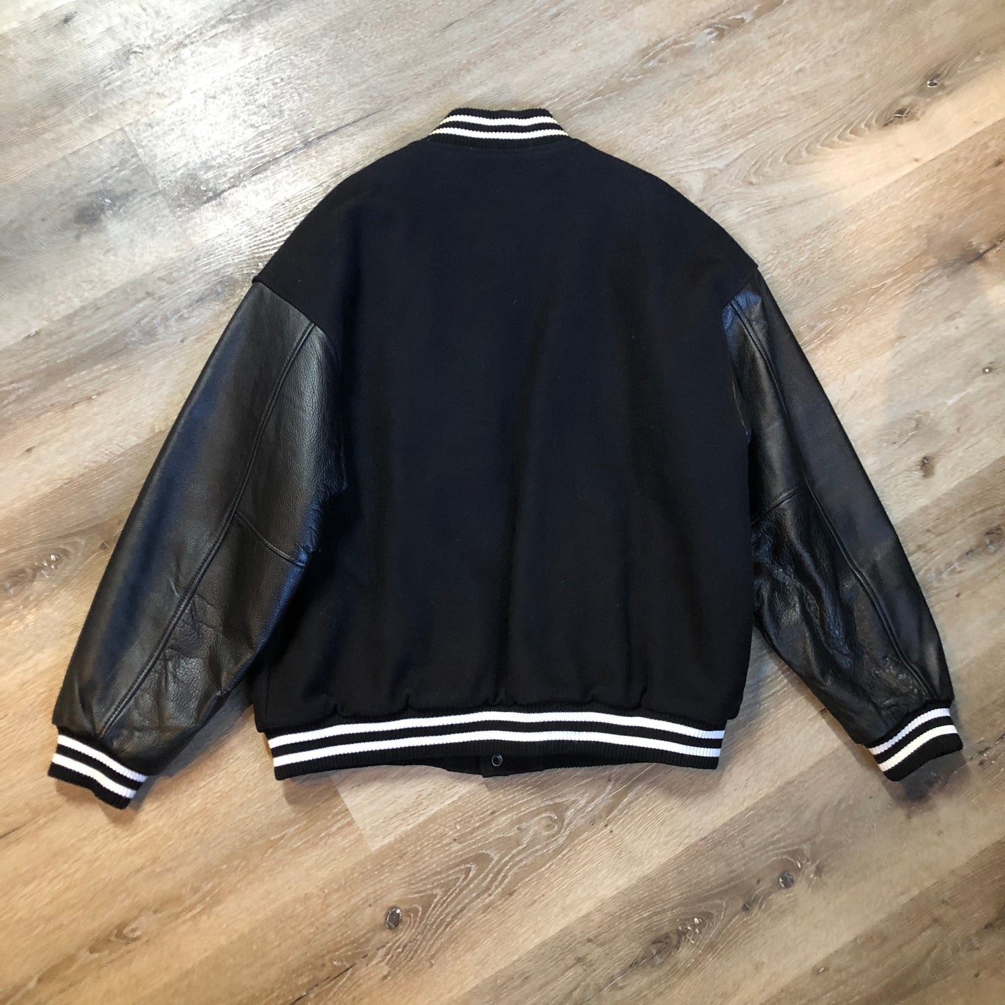 Kingspier Vintage - Coors Light black wool blend varsity jacket with black leather arms, knit trim, slash pockets, snap closure and a quilted lining. Men’s XL.