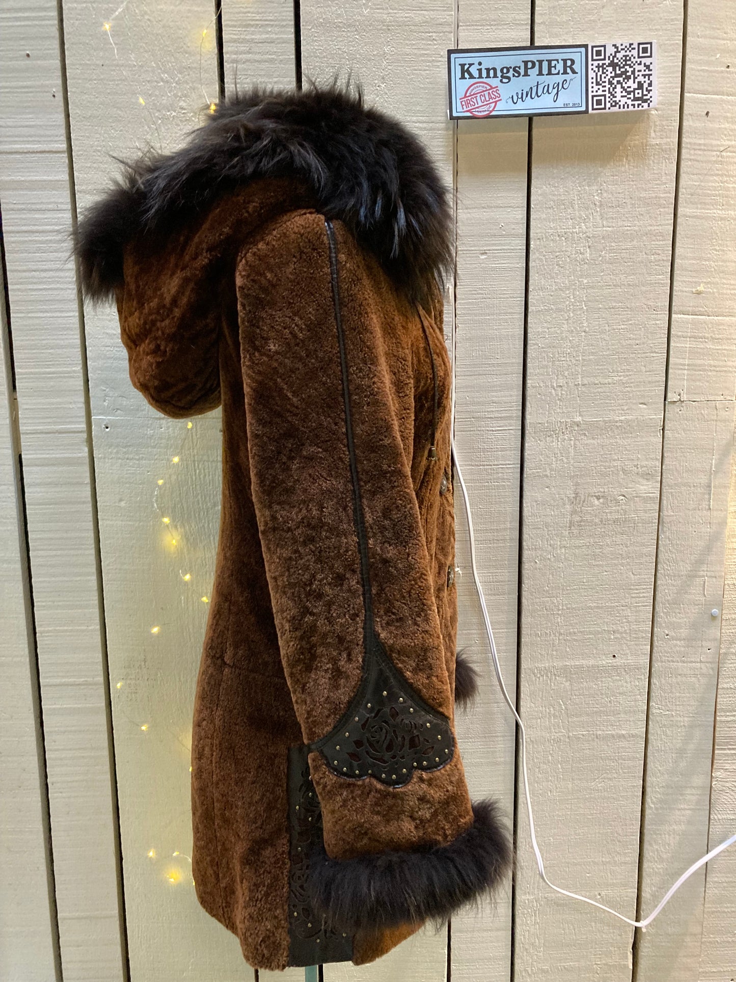 Kingspier Vintage - Vintage Weitral shearling coat with fur trimmed hood and cuffs, unique button closures, leather details with floral motif and two front pockets.
Size large.
Made in Russia.
