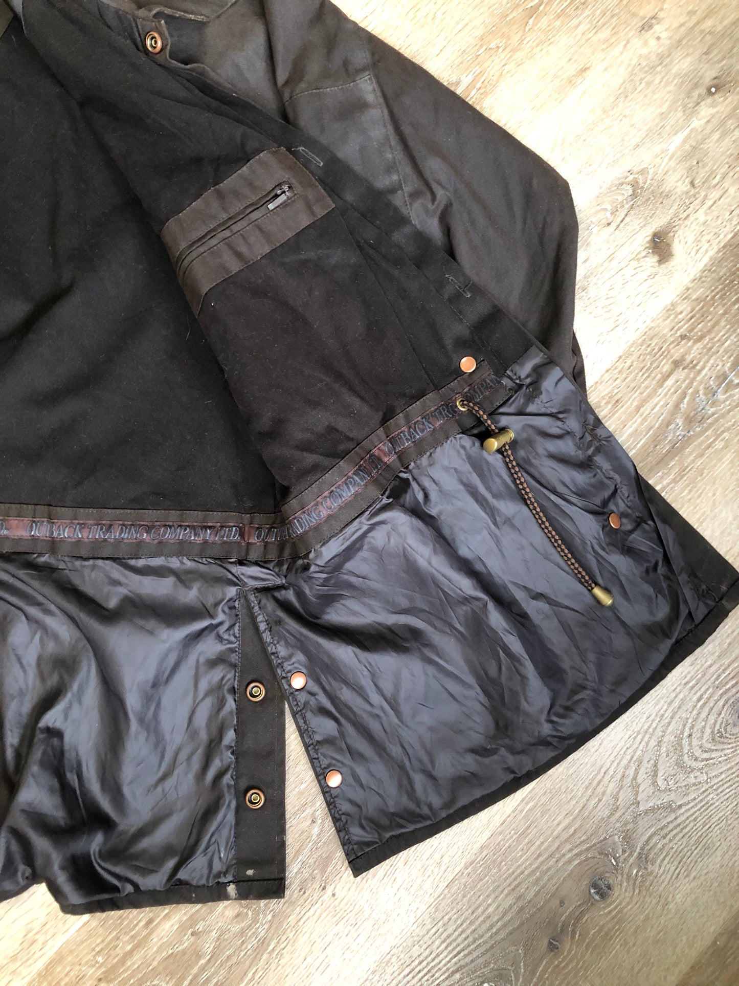 Kingspier Vintage - Outback Trading Co brown cotton oilskin rancher jacket with double snap closures, two snap flap pockets, one inside zip pocket, lightweight lining and drawstring at the waist. Fits large.