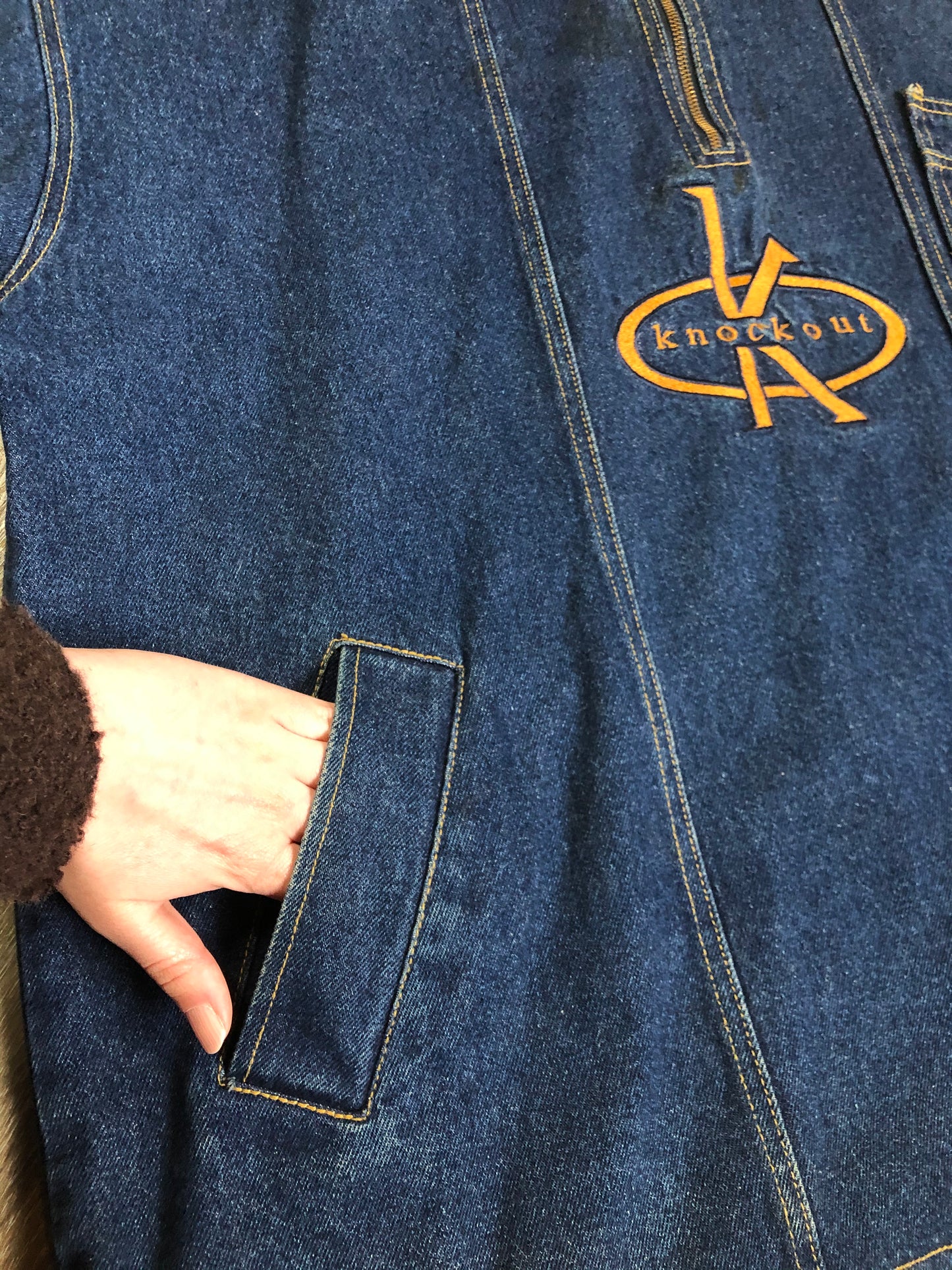 Kingspier Vintage - Vintage Knockout Jeans pullover denim jacket in a medium wash with quarter zip closure, embroidered logo on the front, knit cuffs, slash pockets, one patch pocket on the chest and a leather patch on the back. Size Xl. Made in USA