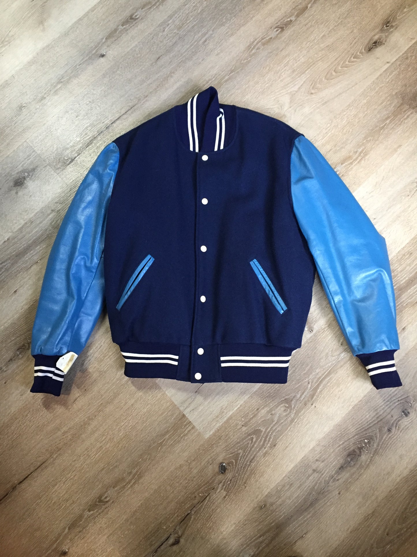 Kingspier Vintage - Blue wool varsity jacket with blue leather arms, snap closures, slash pockets and red quilted lining. Size 44.