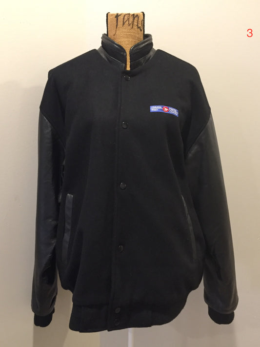 Kingspier Vintage - Canada Post uniform leather and wool blend varsity jacket in black with zipper and snap closures and slash pockets. Size large.