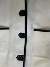 Load image into Gallery viewer, Kingspier Vintage - Genuine Hudson Bay Company 100% virgin wool coat in white with black leather trim, front pockets, flat black buttons and a unique mandarin collar with cape style detail around shoulders. Contains a Hudson’s Bay seal of quality tag. Made in Canada.
